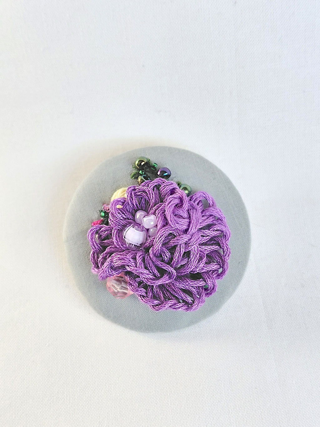 Decorative purple flower brooch on grey background