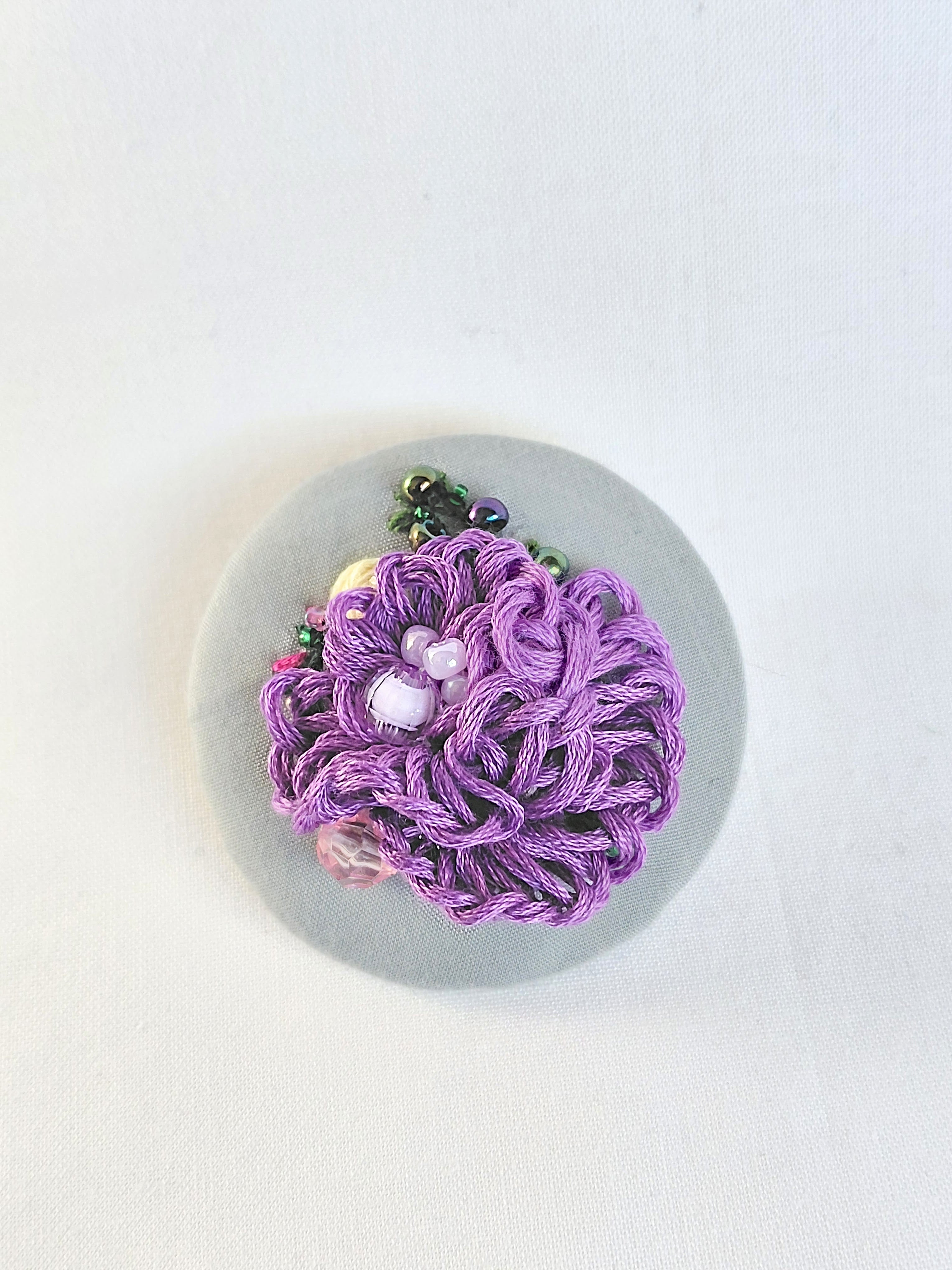 Decorative purple flower brooch on grey background