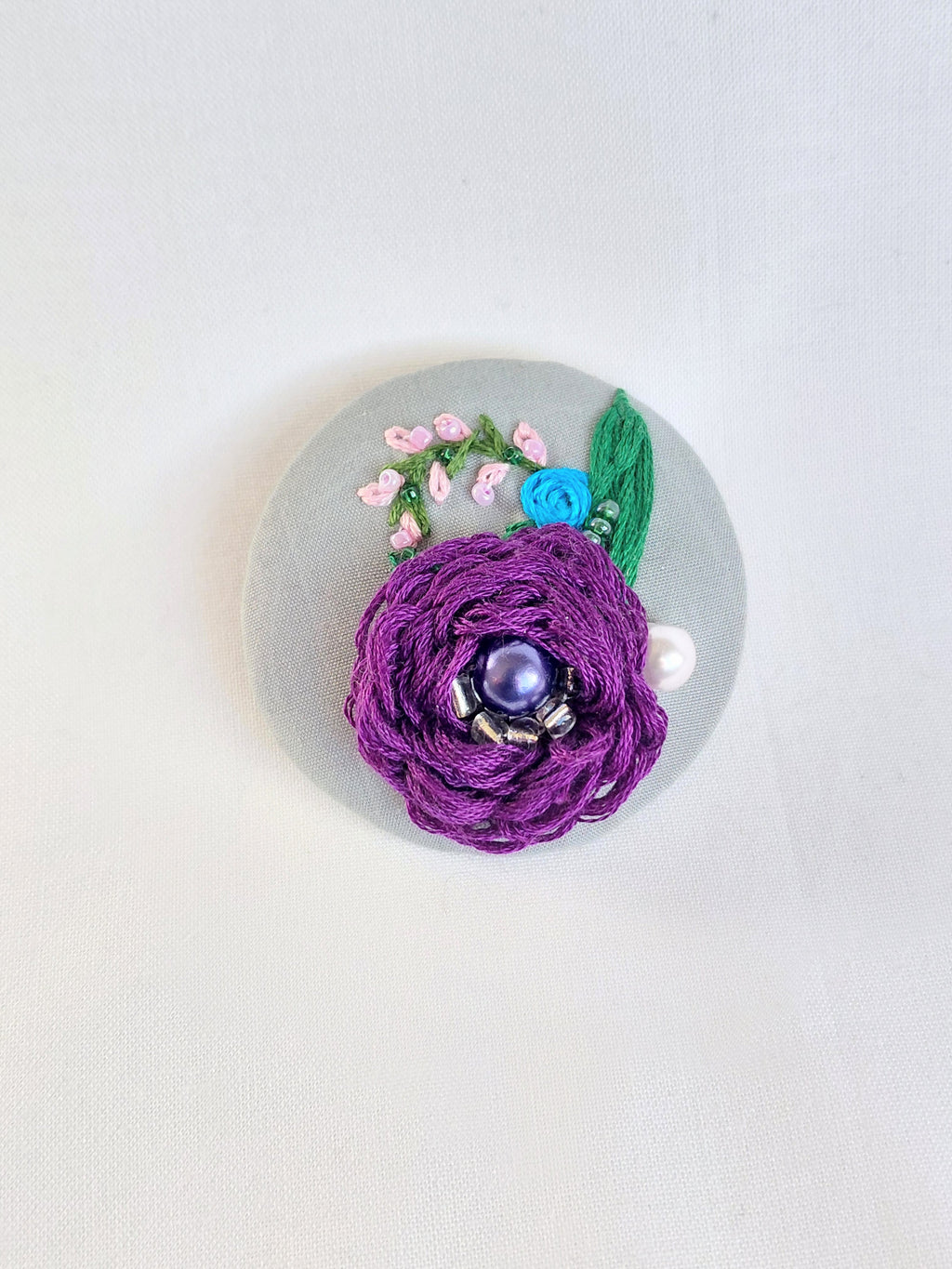 Decorative purple flower brooch on grey background