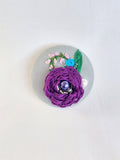 Decorative purple flower brooch on grey background