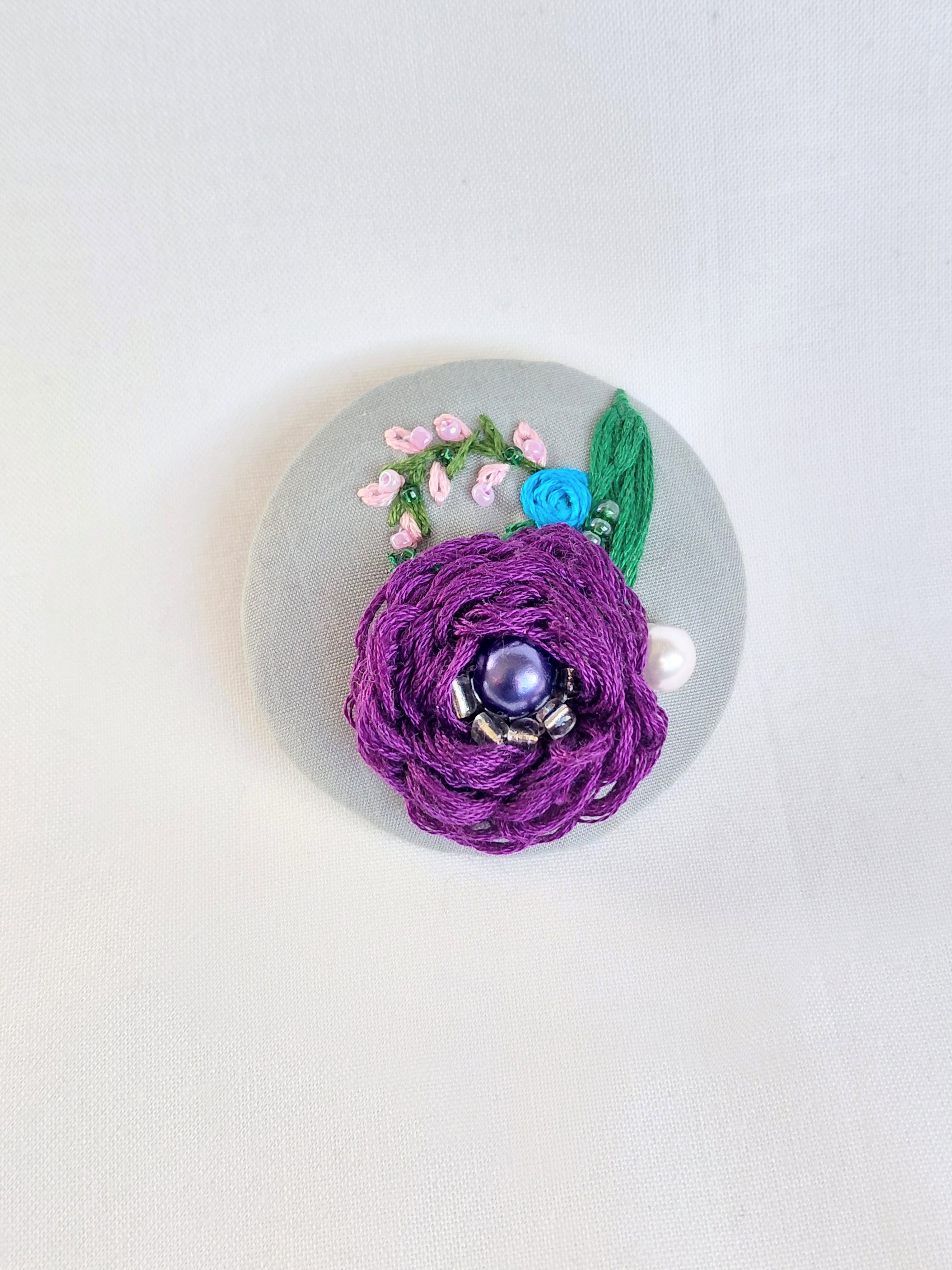 Decorative purple flower brooch on grey background