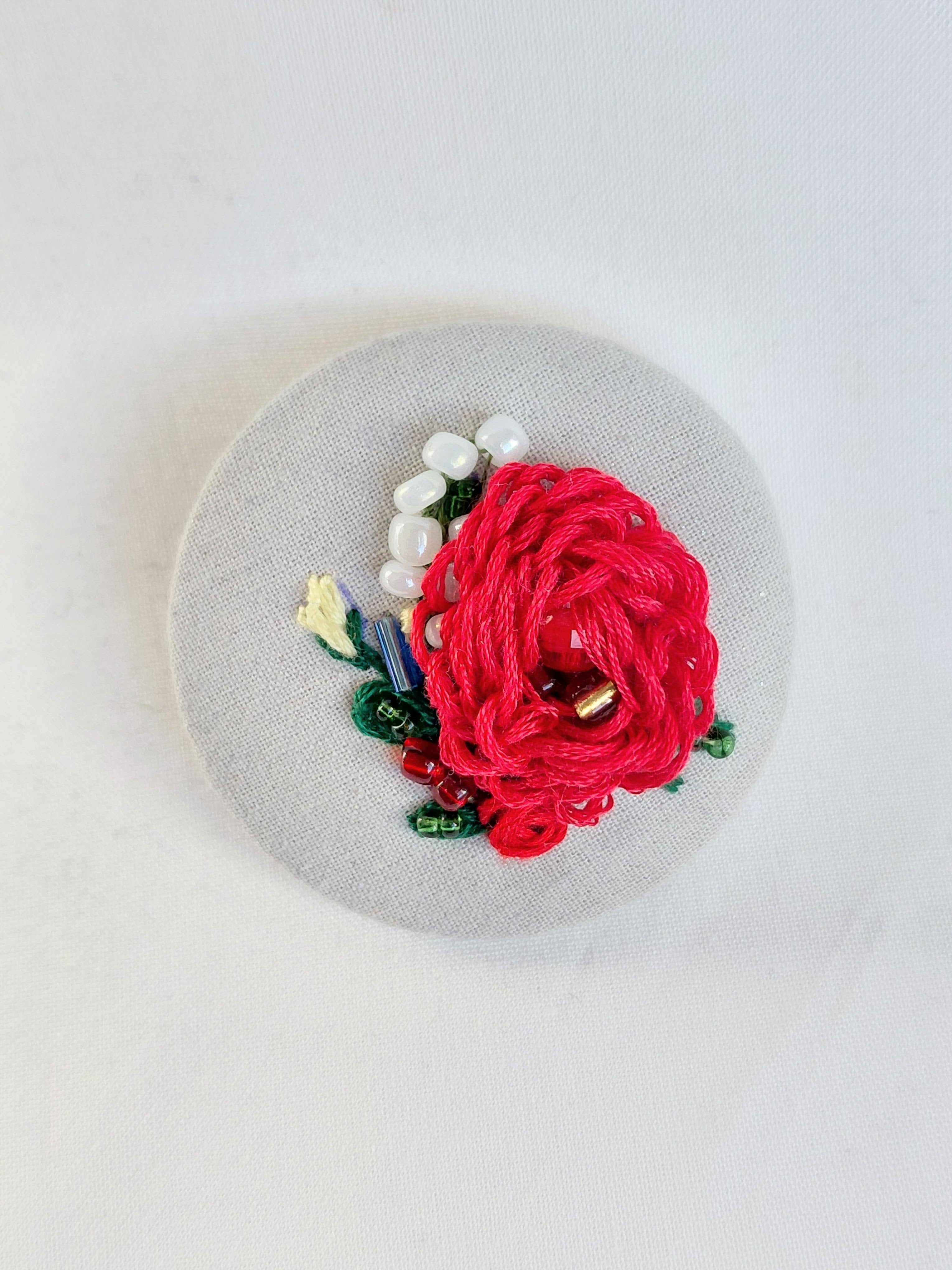 Decorative red flower brooch on grey spec background