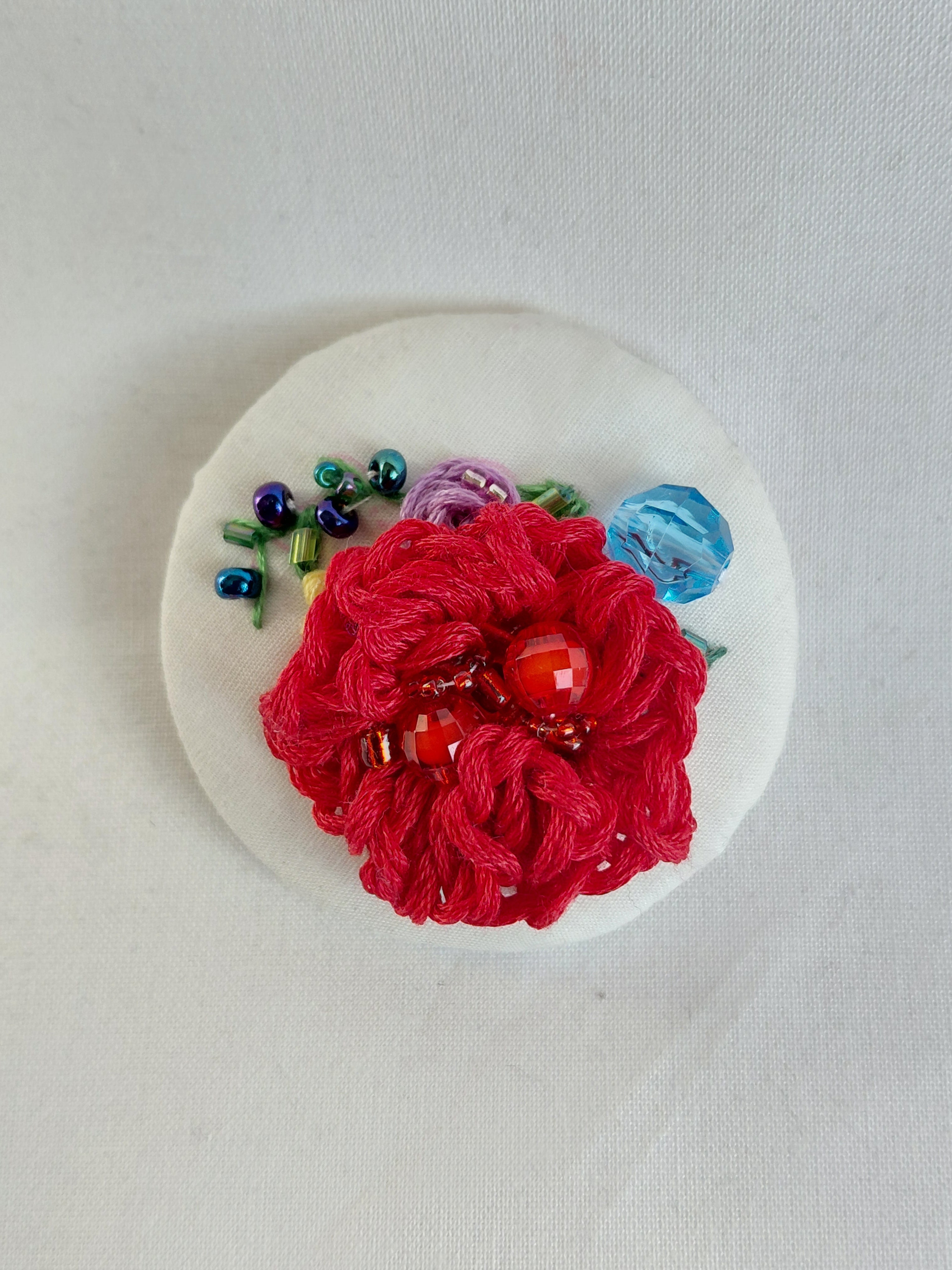 Decorative red flower brooch on white background