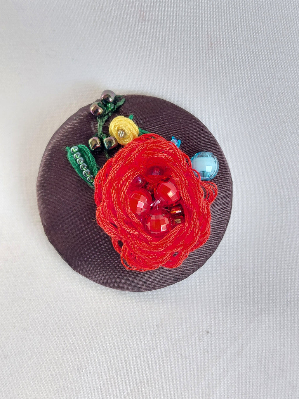 Decorative red flower brooch on brown background