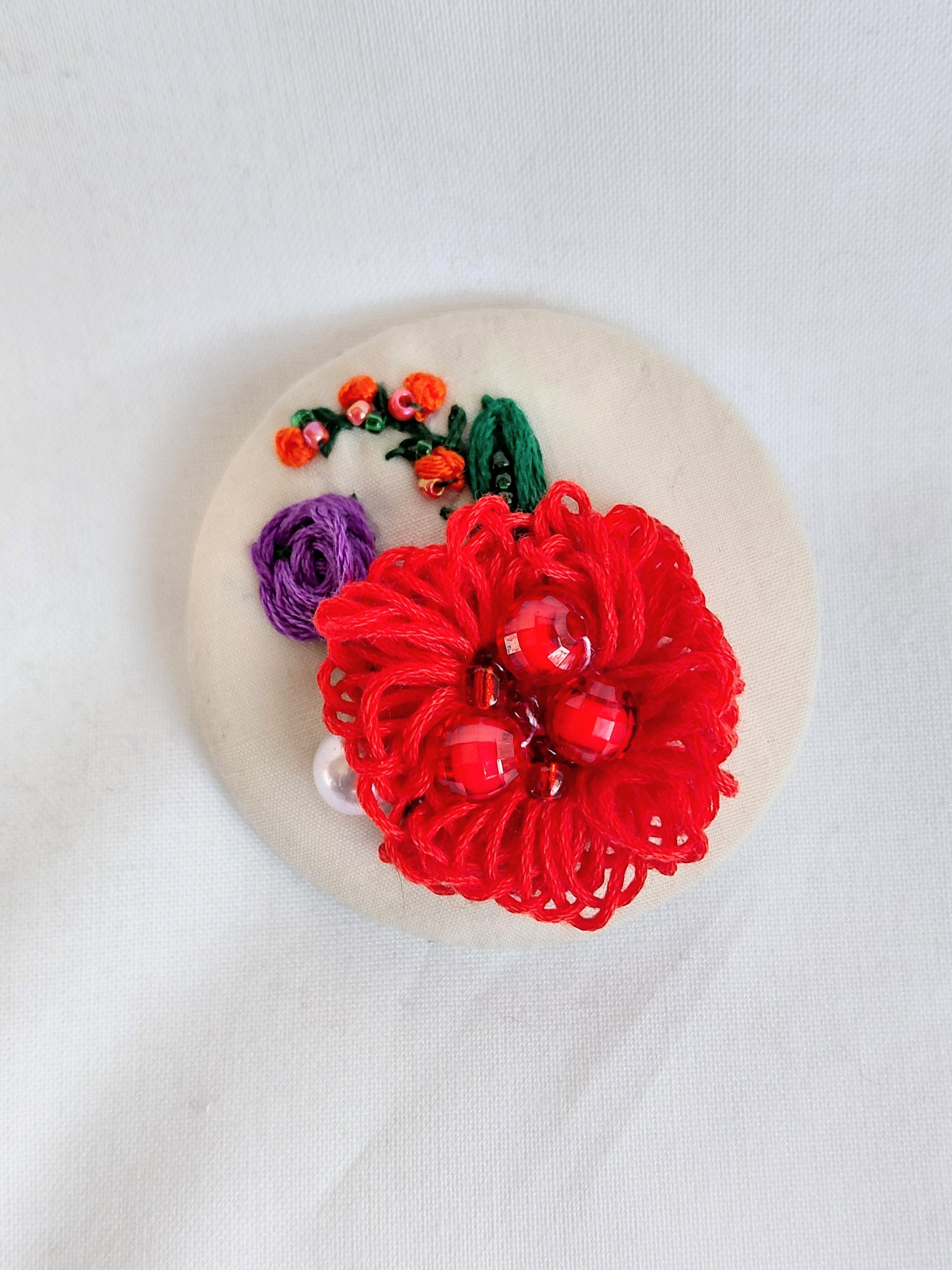 Decorative red flower brooch on cream background