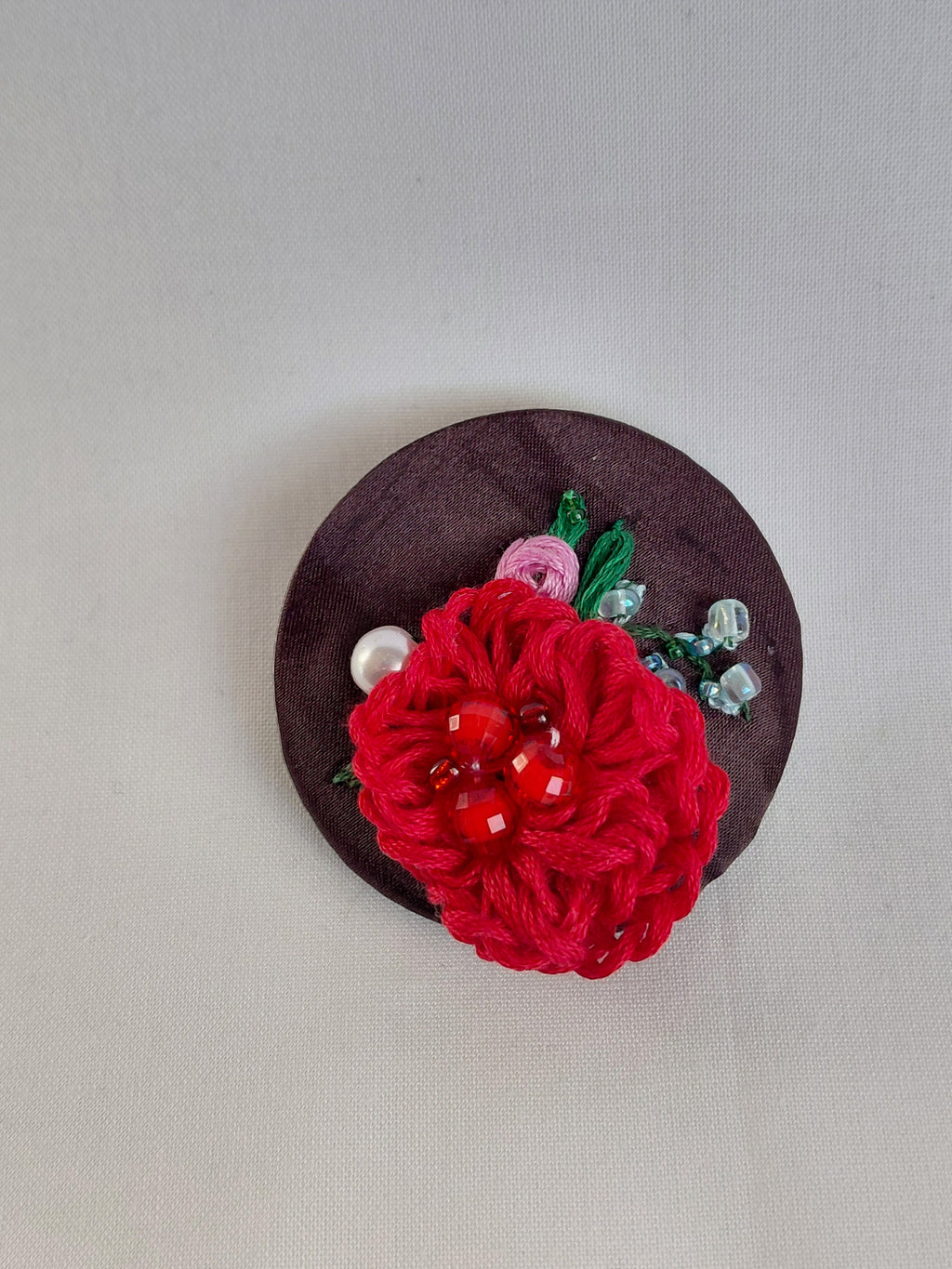 Decorative red flower brooch on brown background