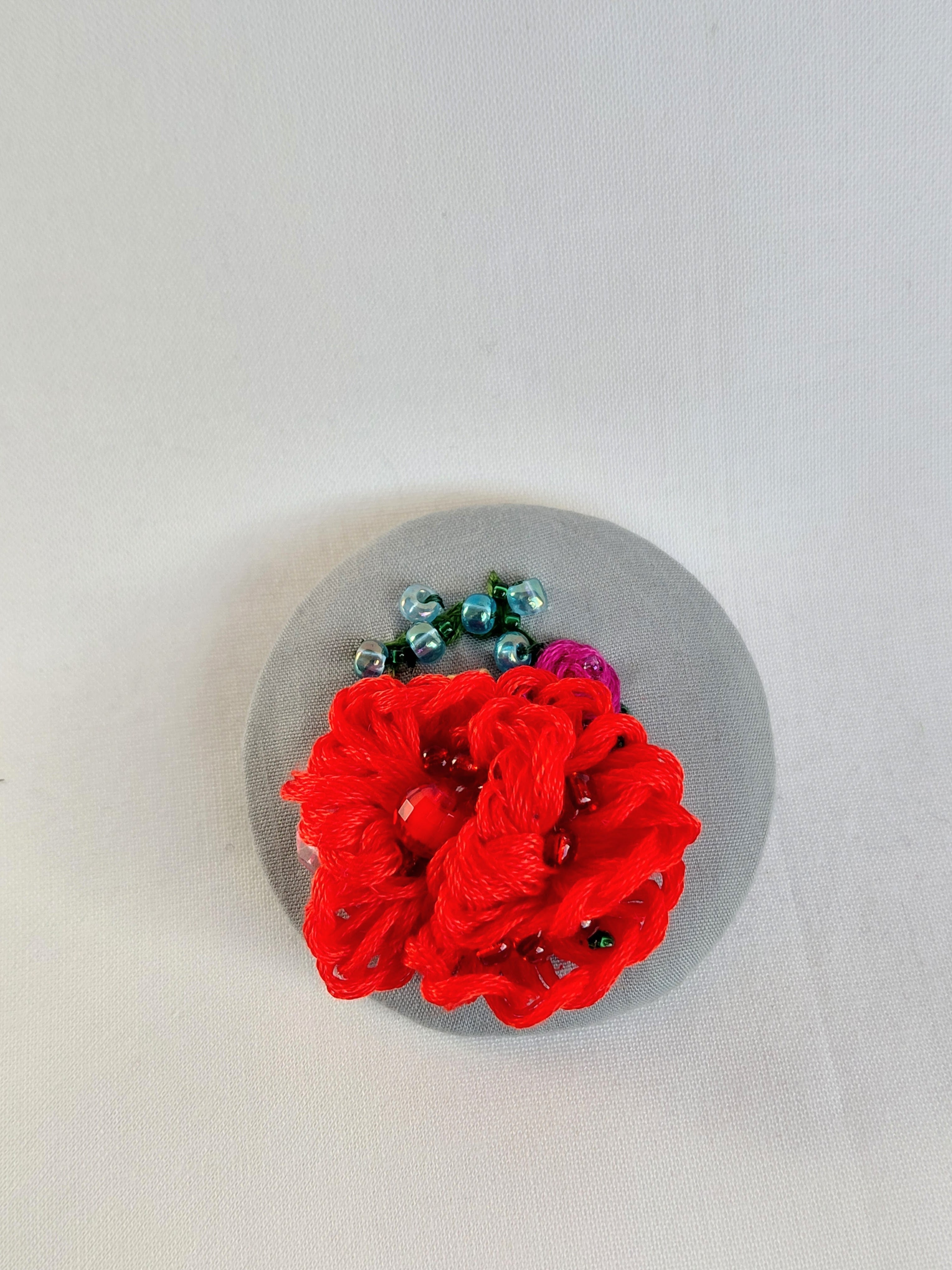 Decorative red flower brooch on grey background
