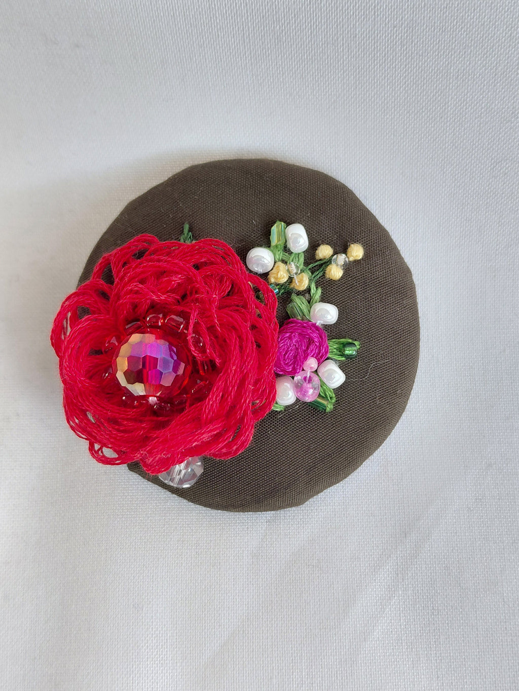 Decorative red flower brooch on olive background