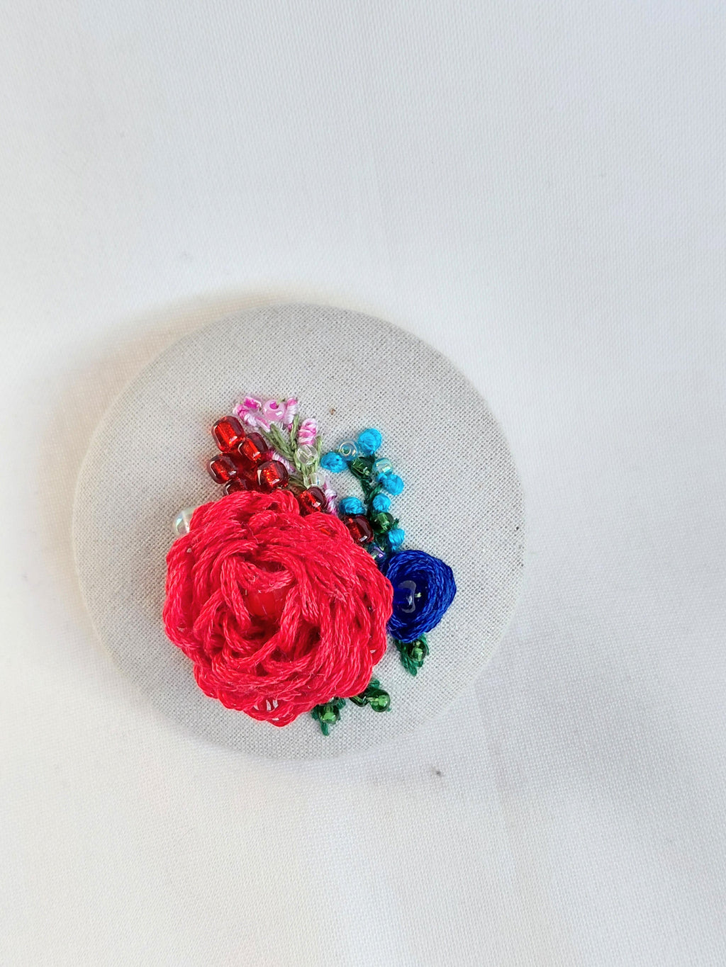 Decorative red flower brooch on grey spec background