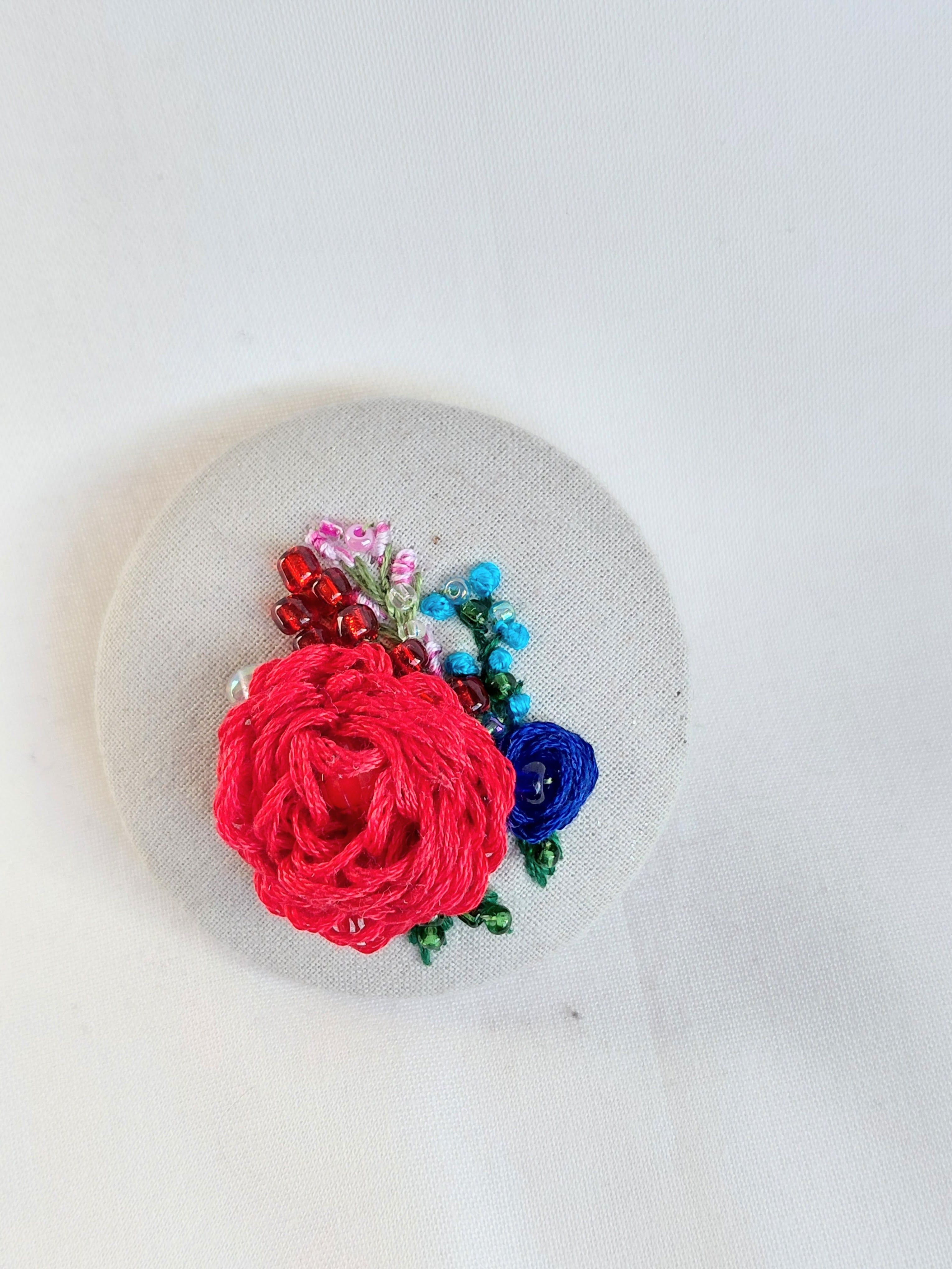 Decorative red flower brooch on grey spec background