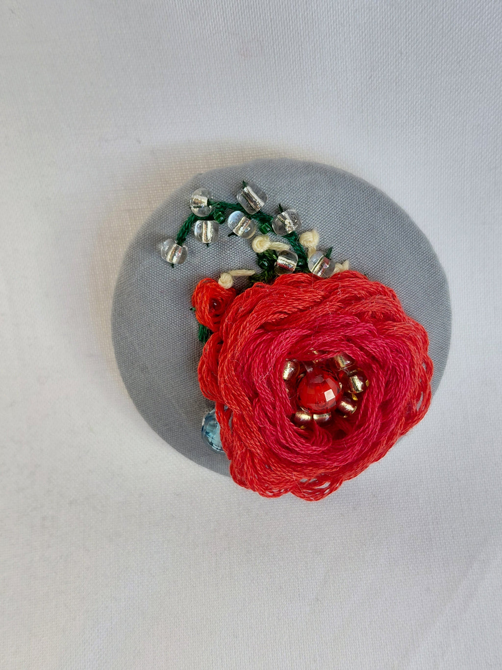 Decorative red flower brooch on grey background
