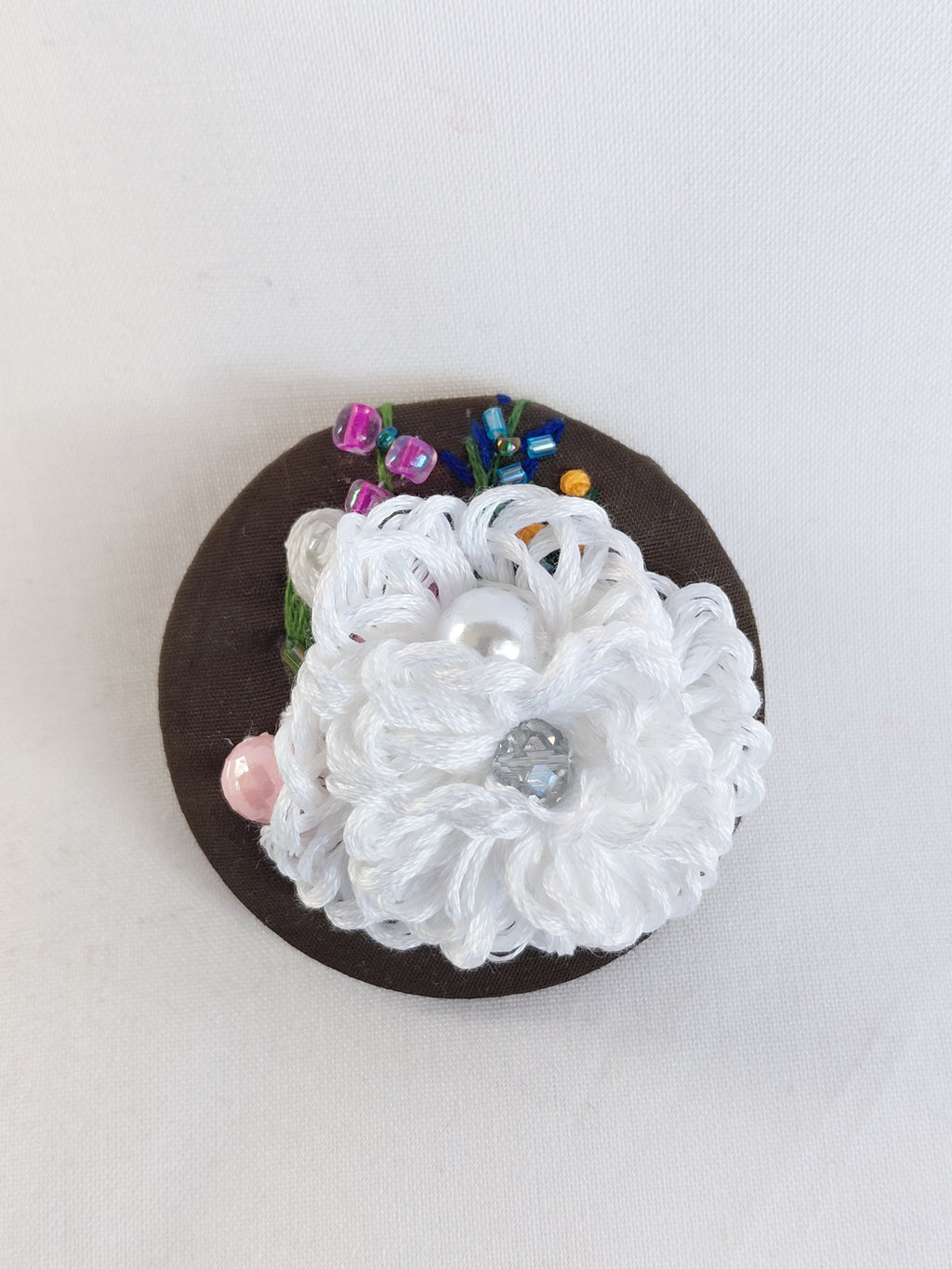 Decorative white flower brooch on olive background