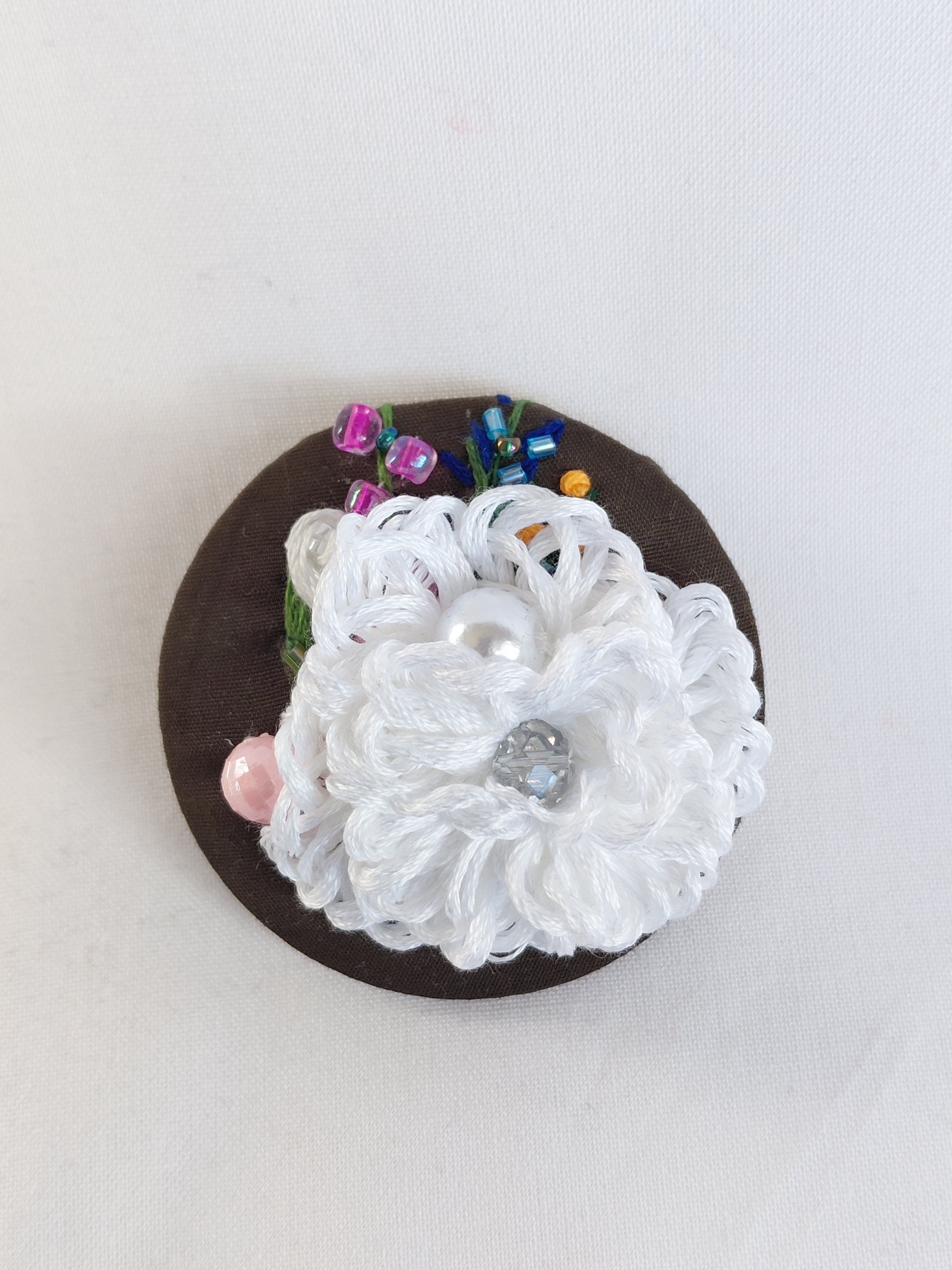 Decorative white flower brooch on olive background