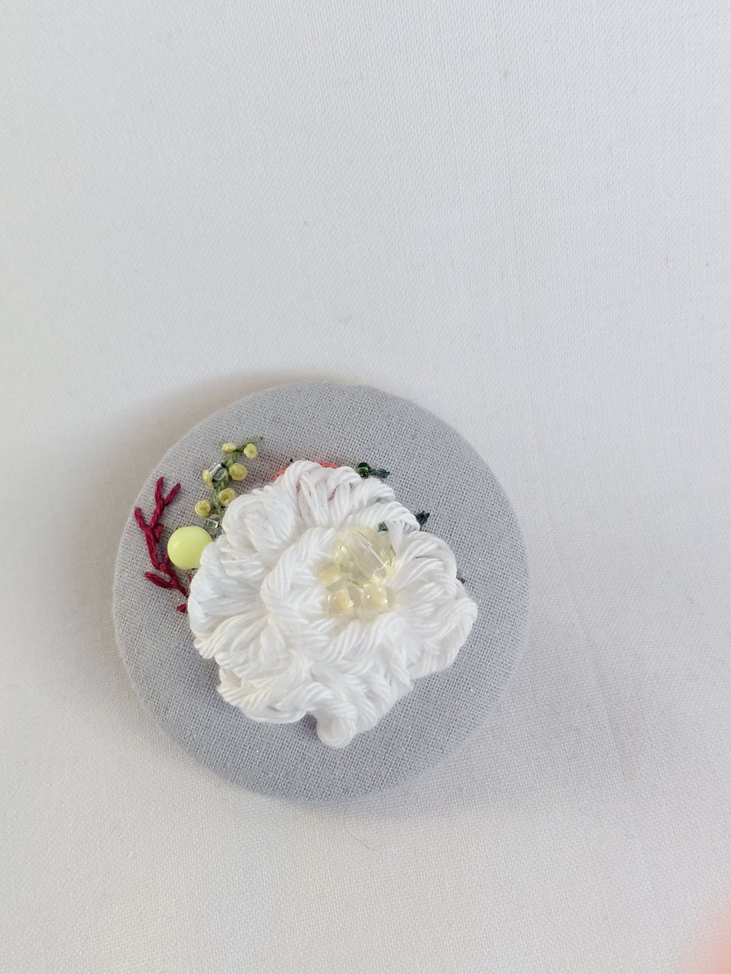 Decorative white flower brooch on blue spec background