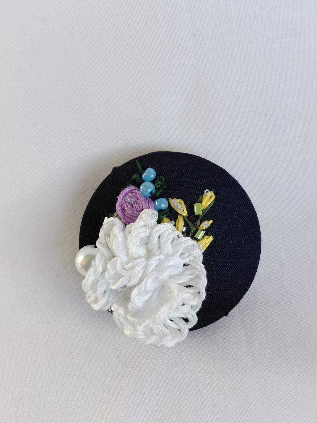 Decorative white flower brooch on black background