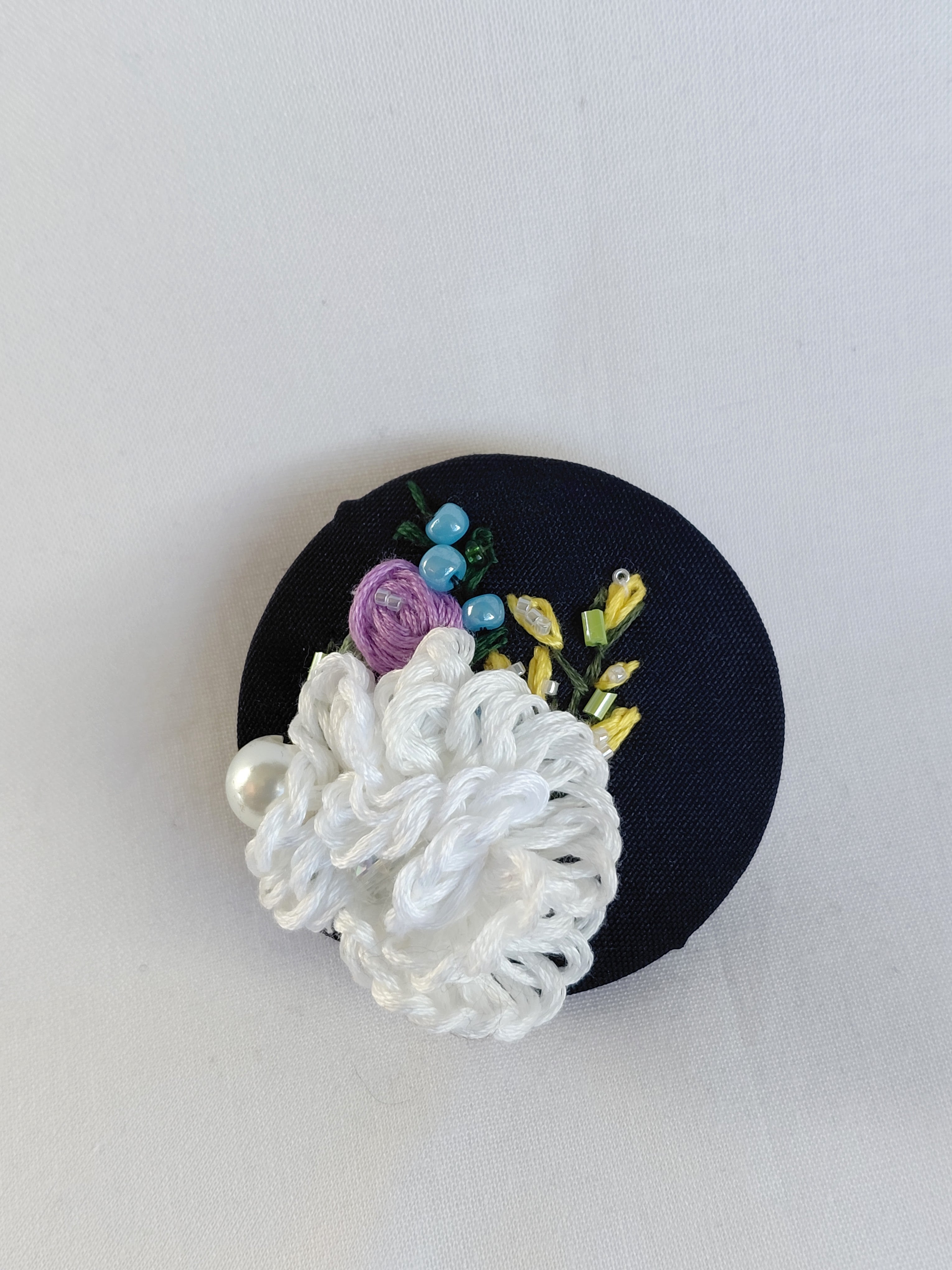 Decorative white flower brooch on black background