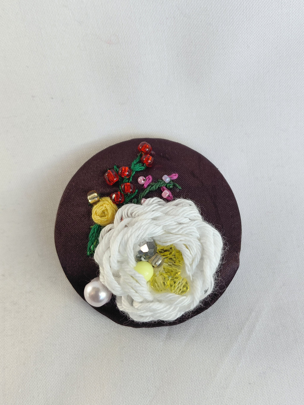 Decorative white flower brooch on brown background