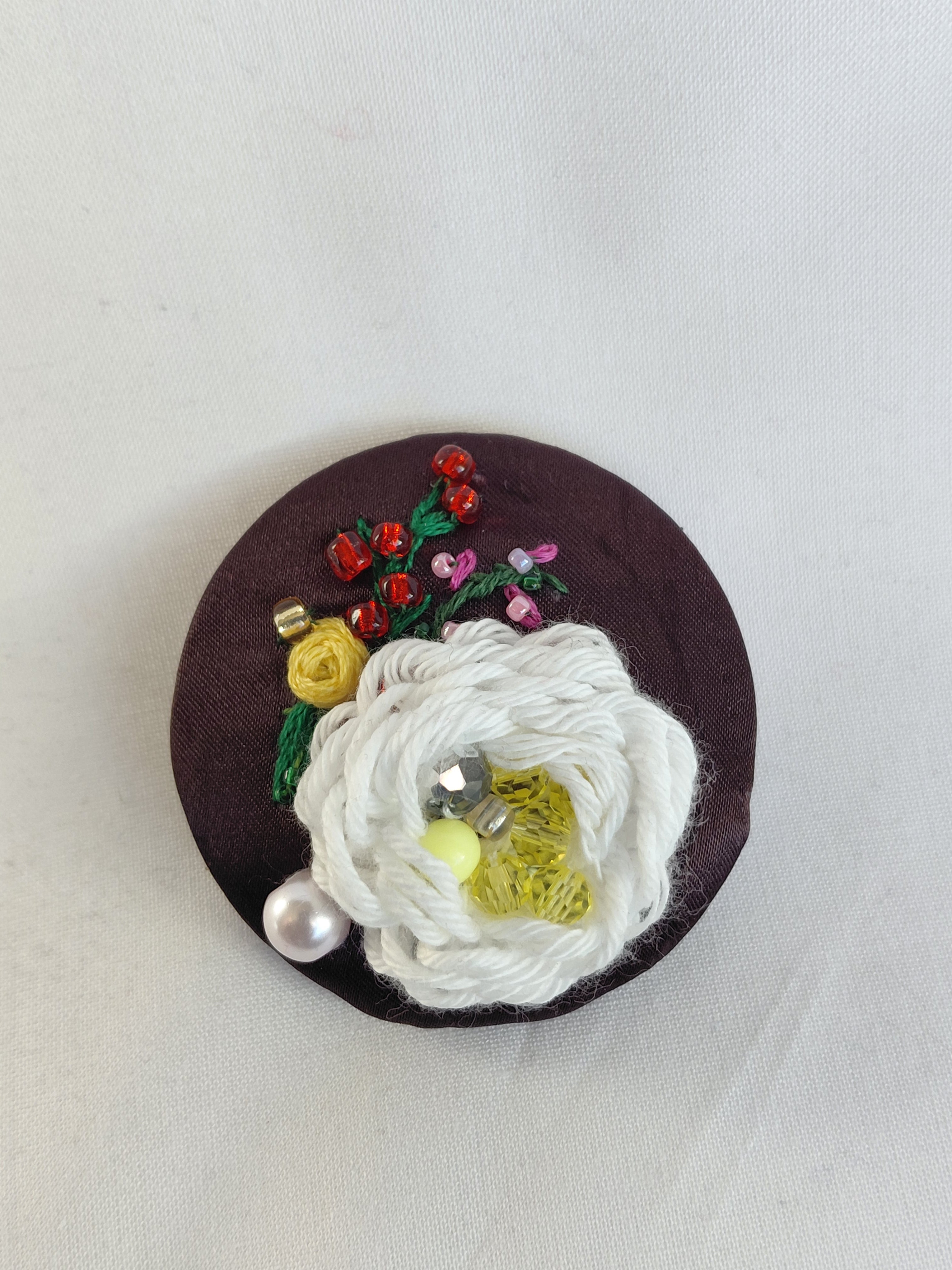 Decorative white flower brooch on brown background