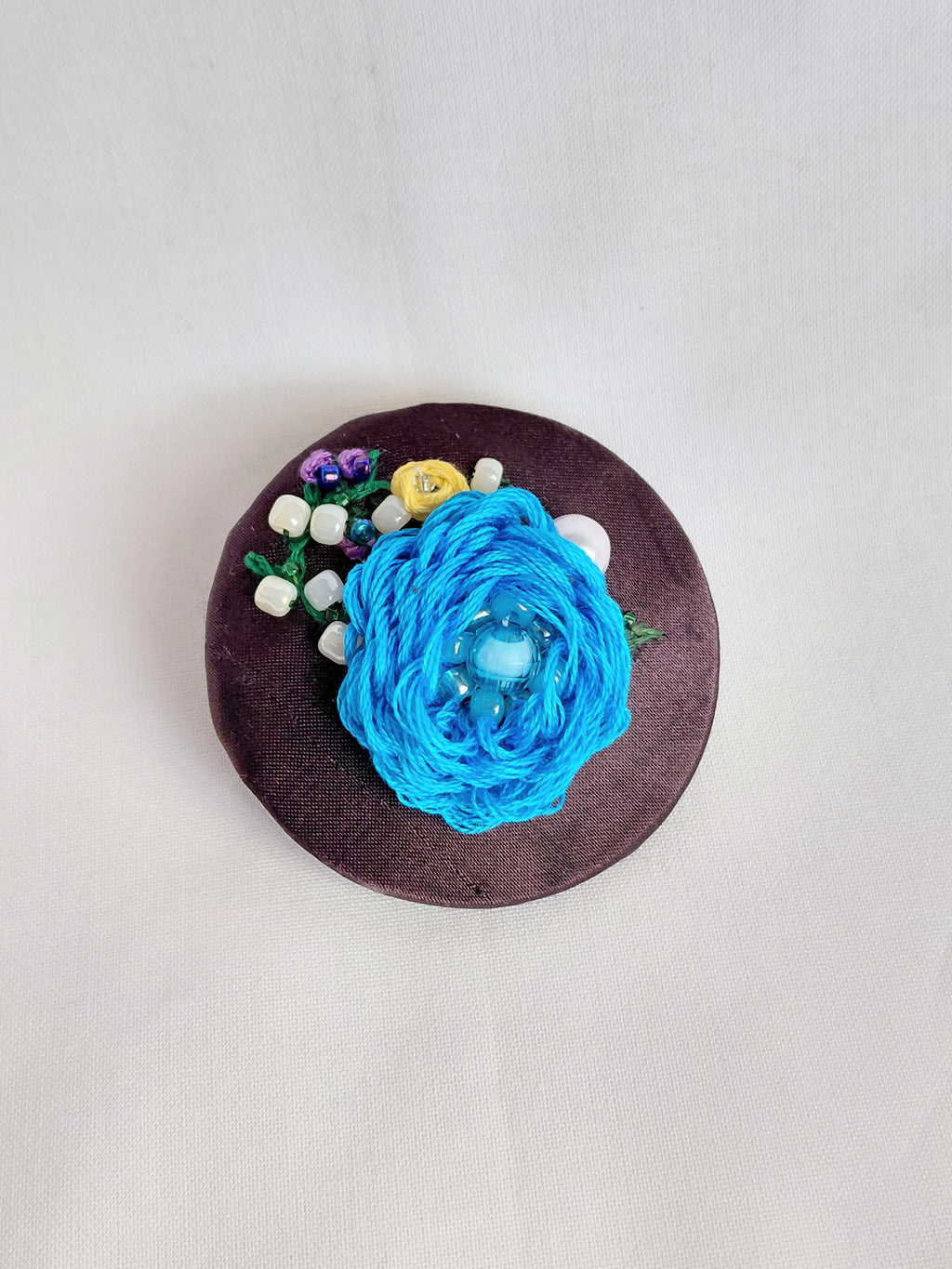 Decorative blue flower brooch on brown background