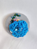 Decorative blue flower brooch on grey  background