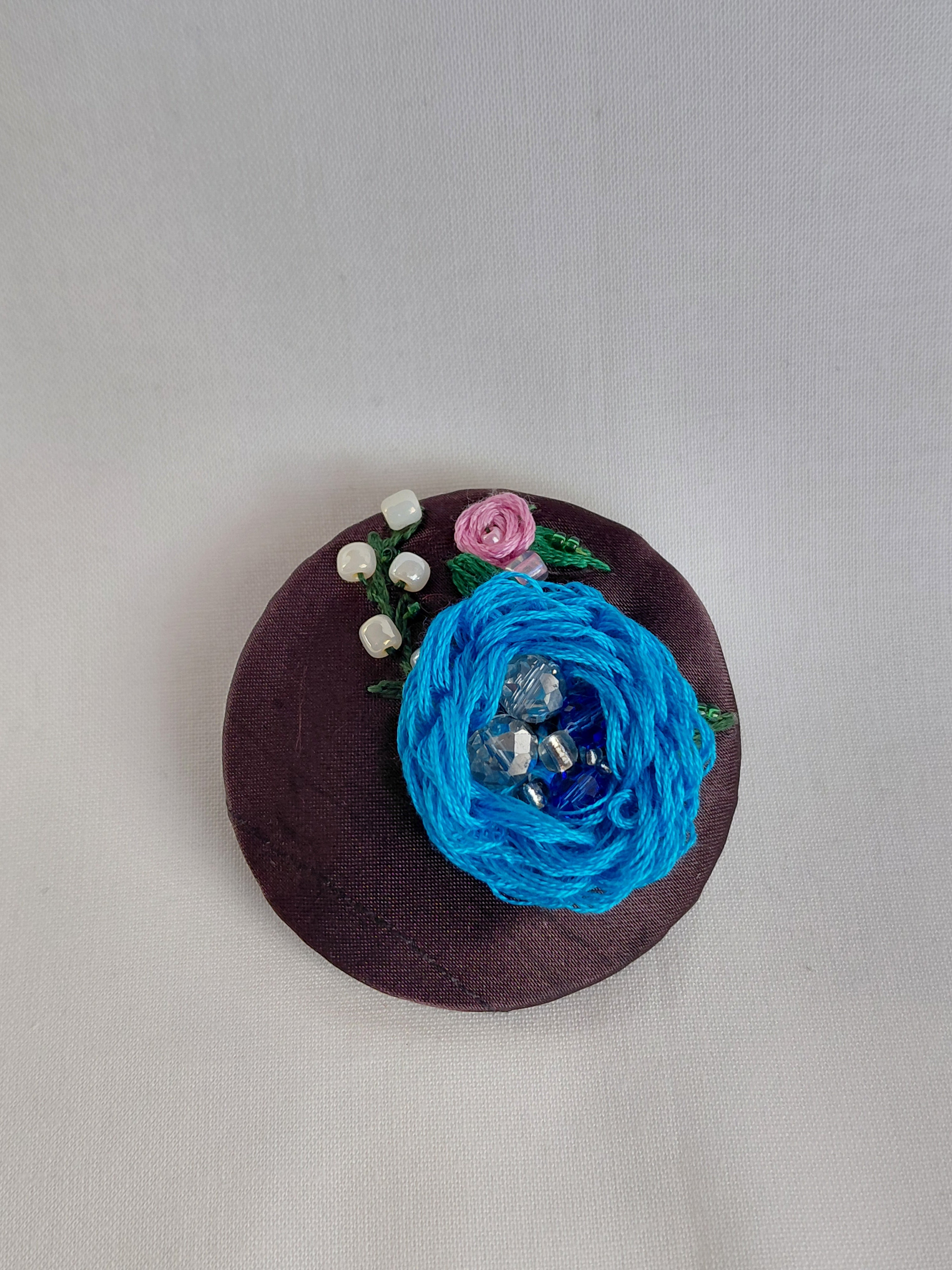 Decorative blue flower brooch on brown background