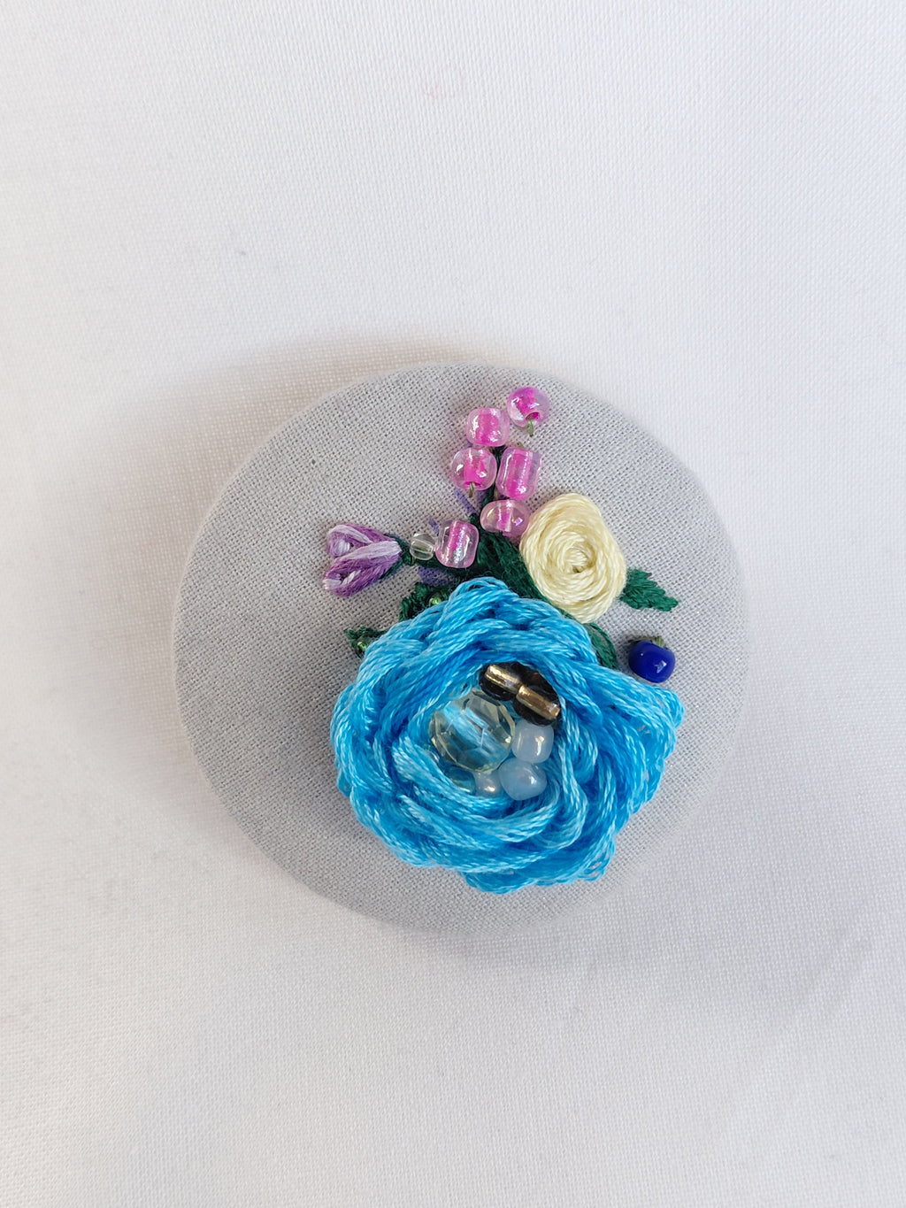 Decorative blue flower brooch on grey spec background