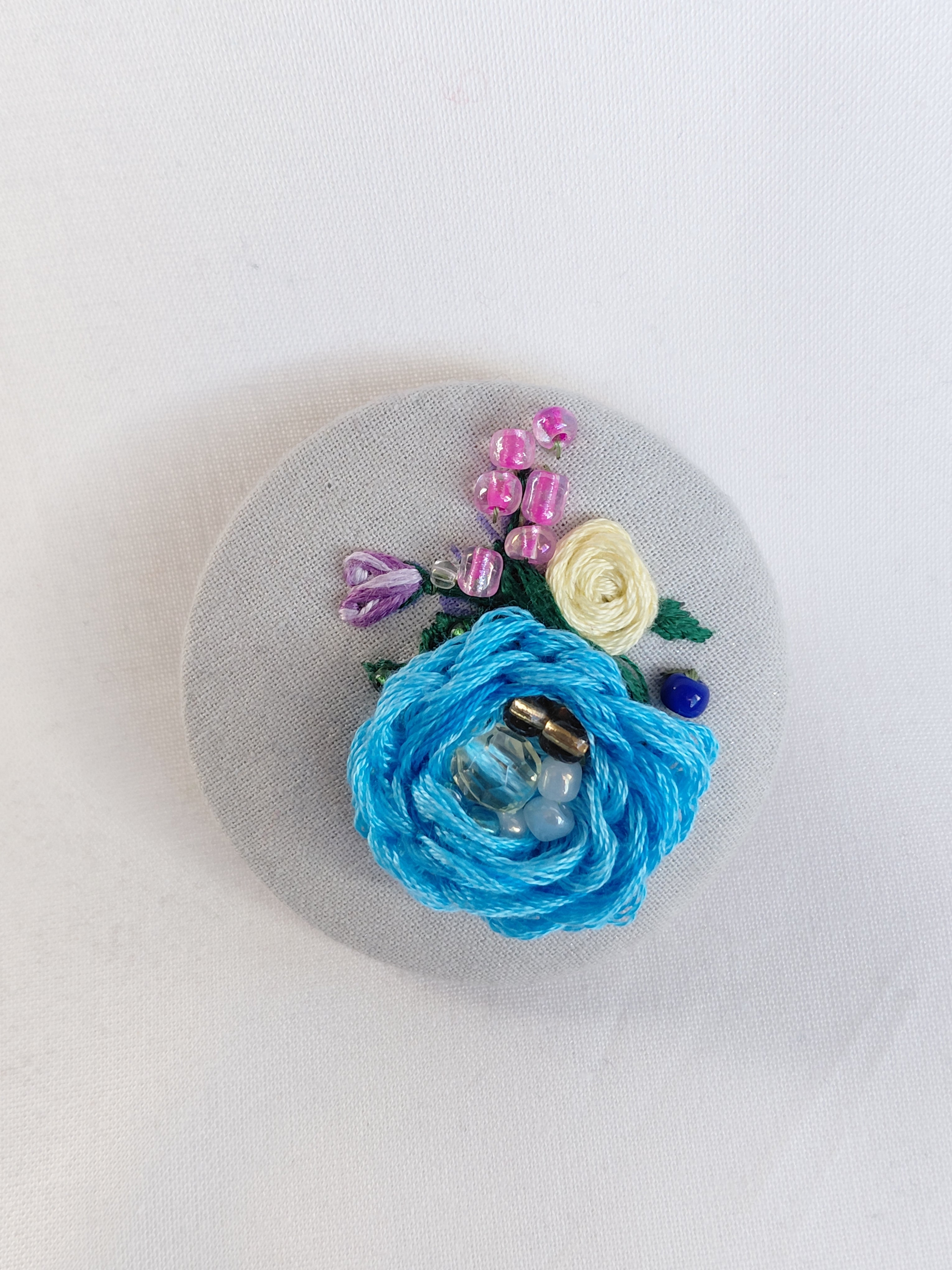 Decorative blue flower brooch on grey spec background