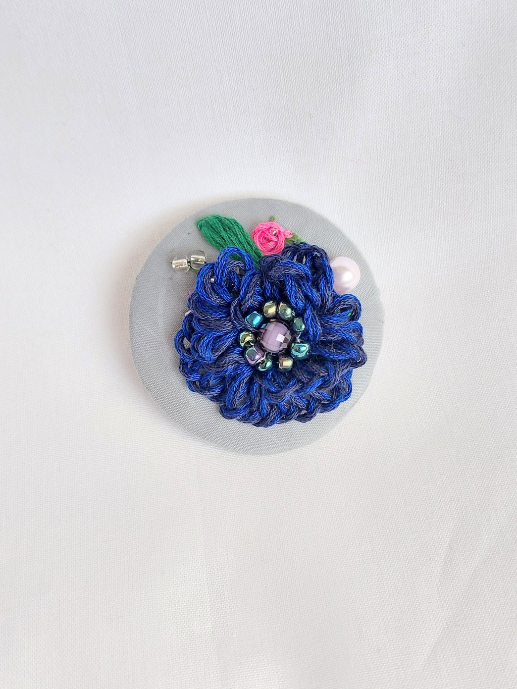 Decorative blue flower brooch on grey background