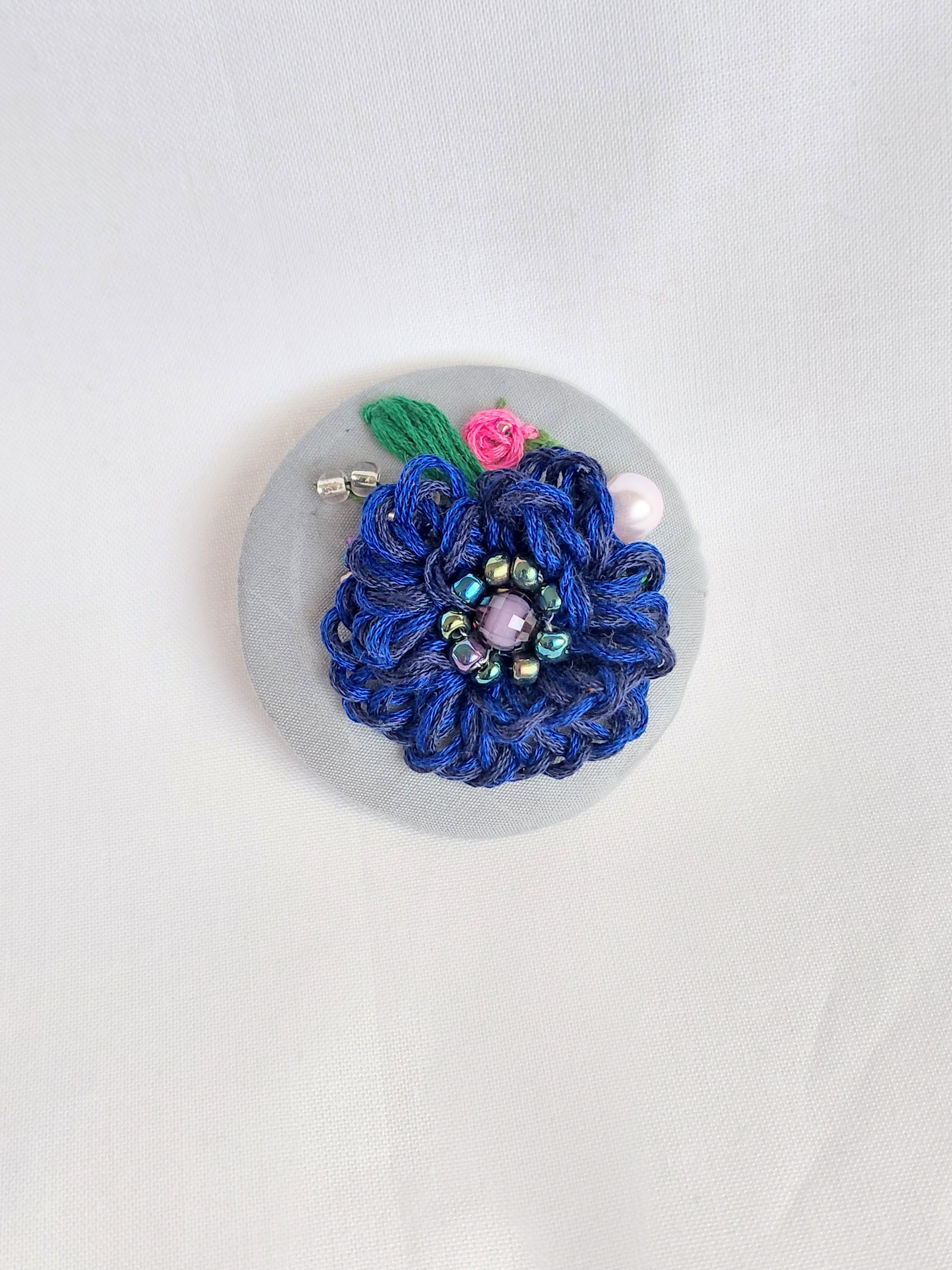 Decorative blue flower brooch on grey background