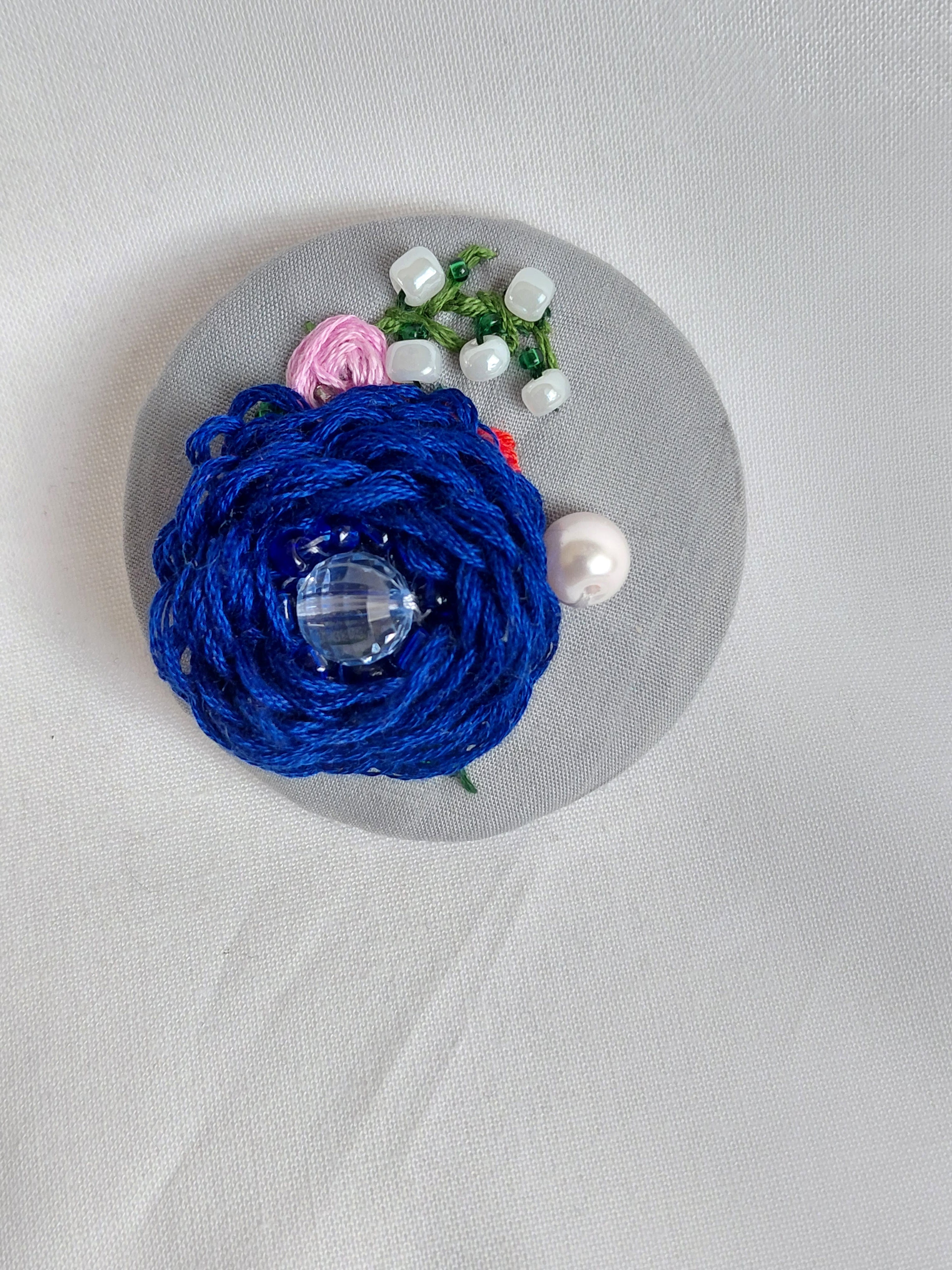 Decorative blue flower brooch on grey background