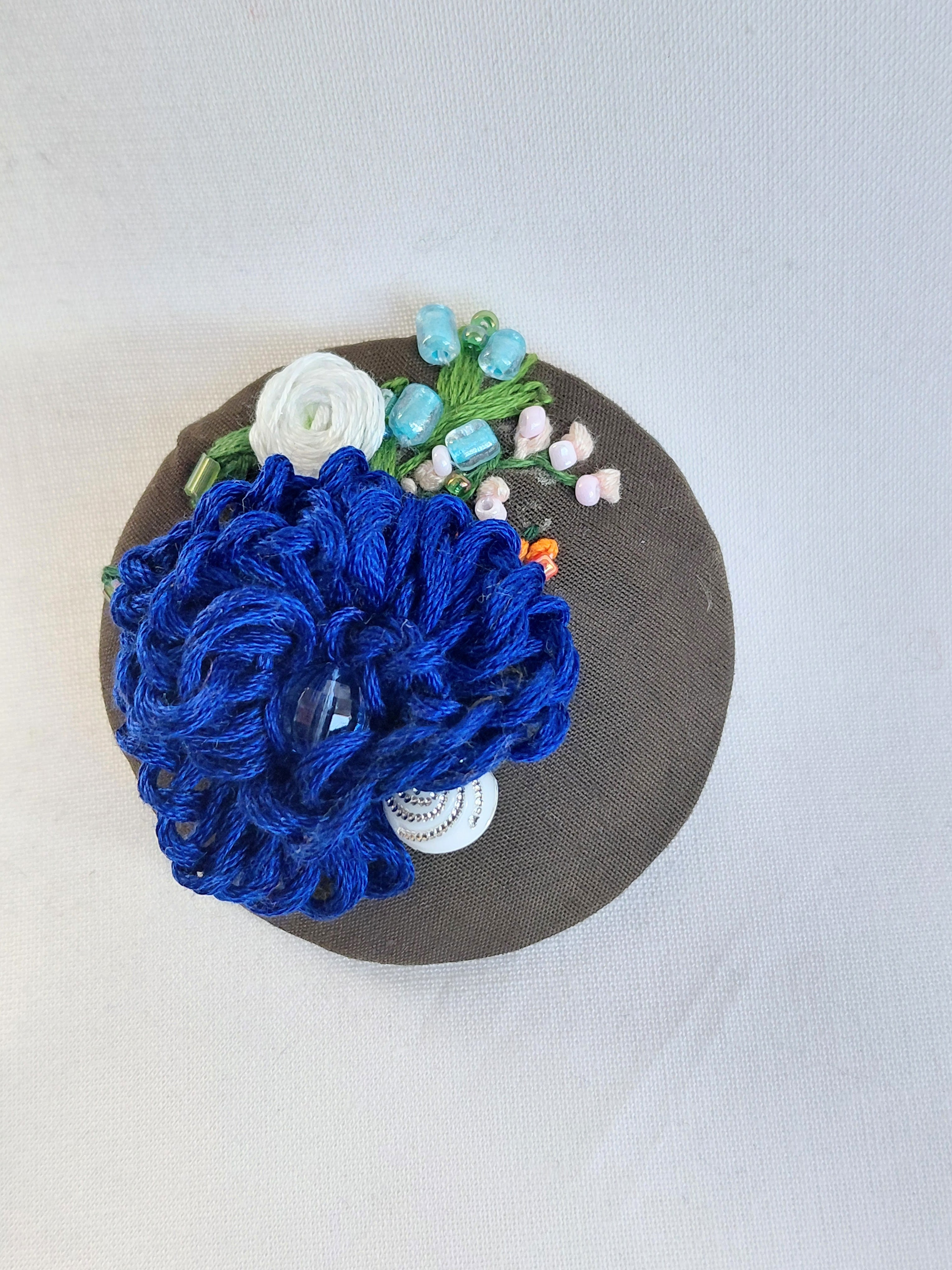 Decorative blue flower brooch on olive background
