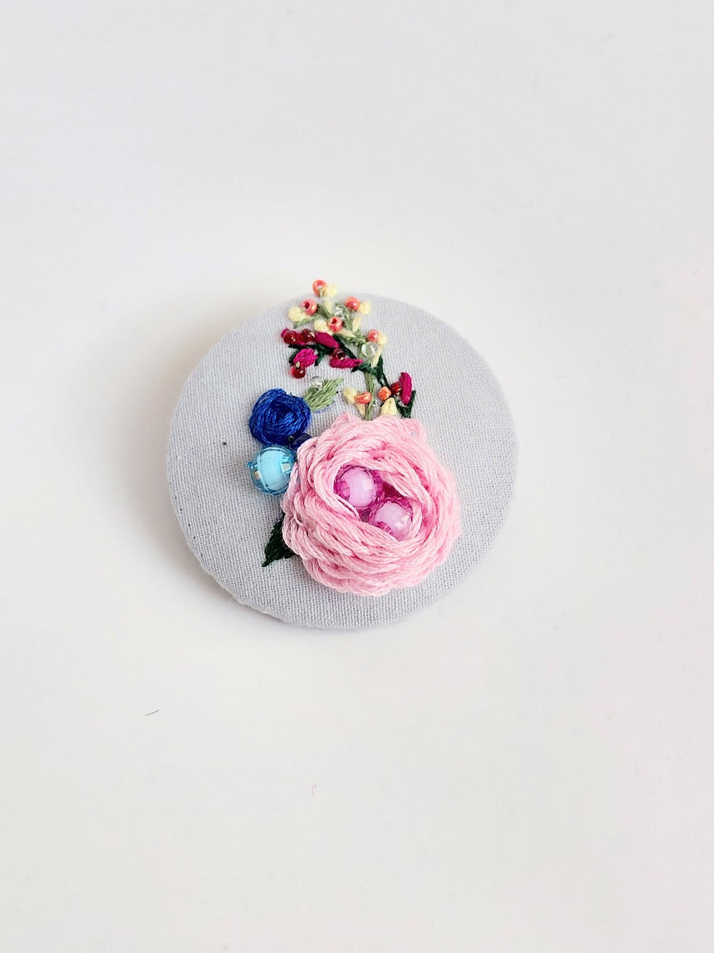 Decorative pink flower brooch on grey background