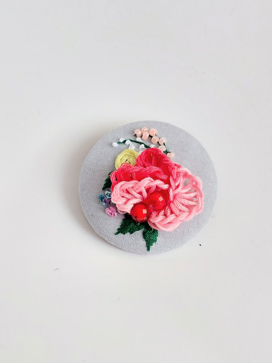 Decorative pink flower brooch on grey background