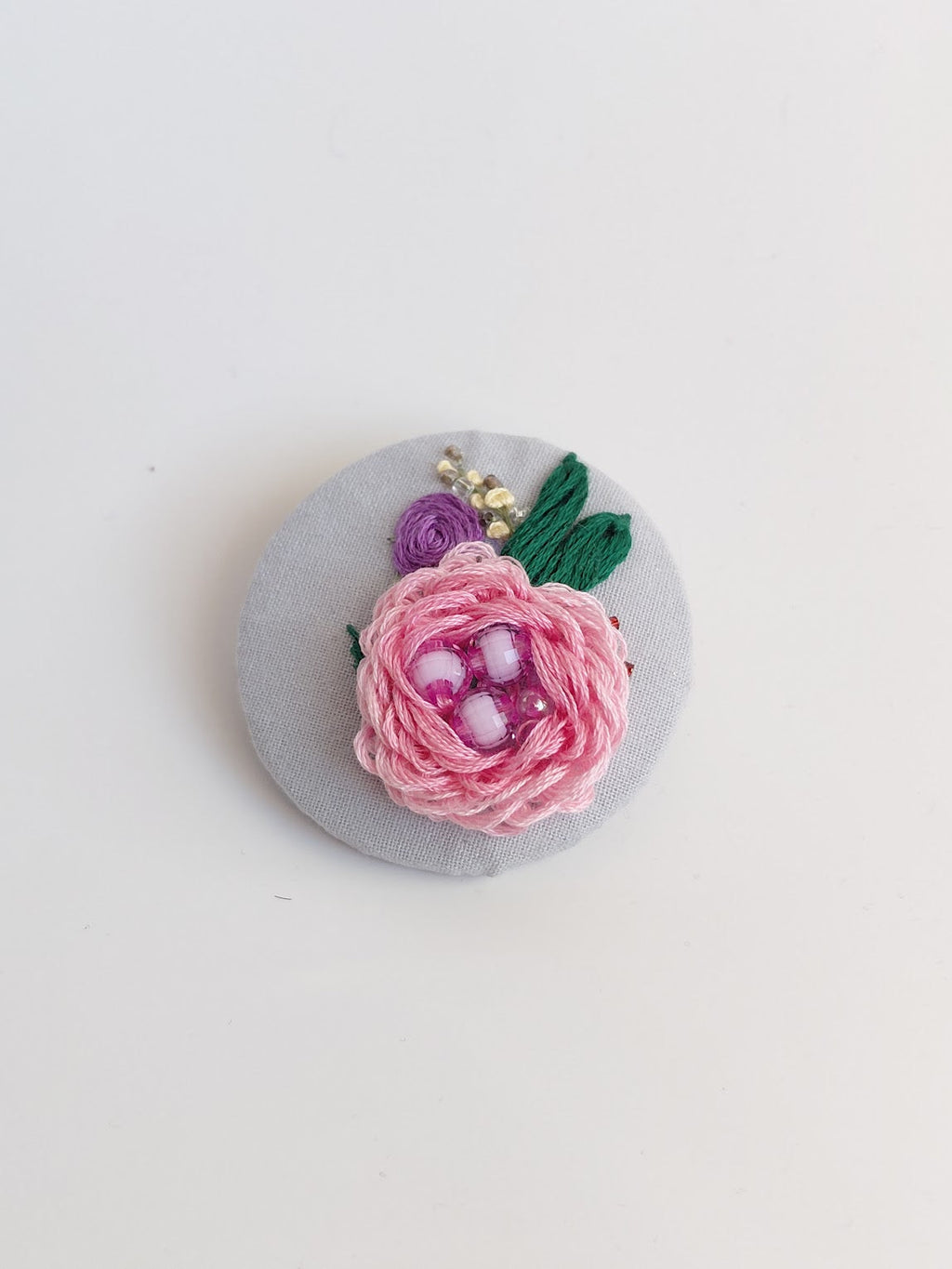 Decorative pink flower brooch on grey background
