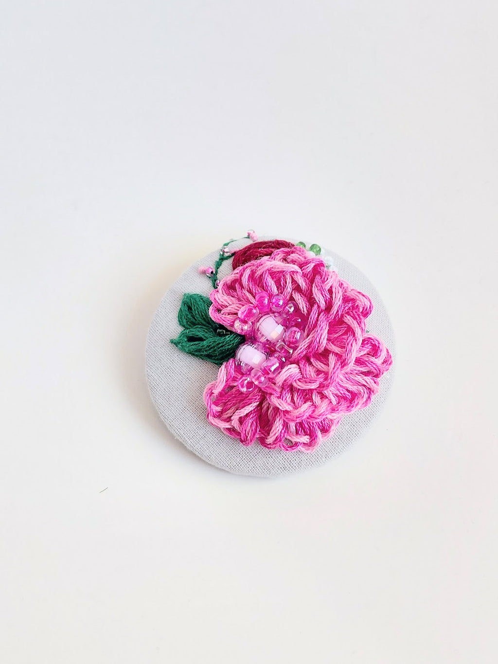 Decorative pink flower brooch on grey background