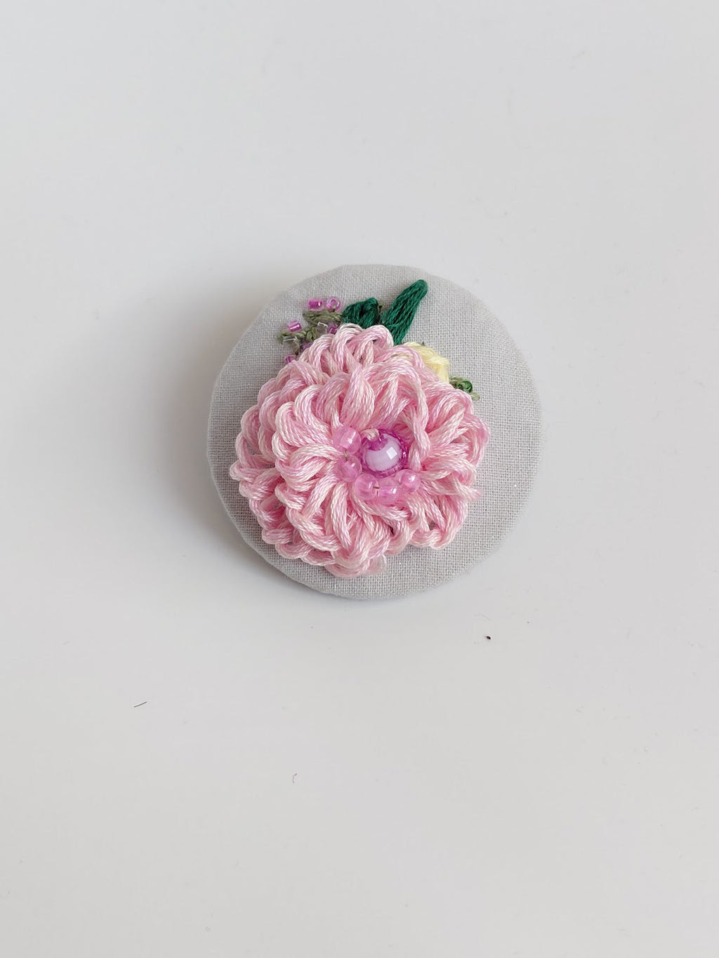 Decorative pink flower brooch on grey spec background