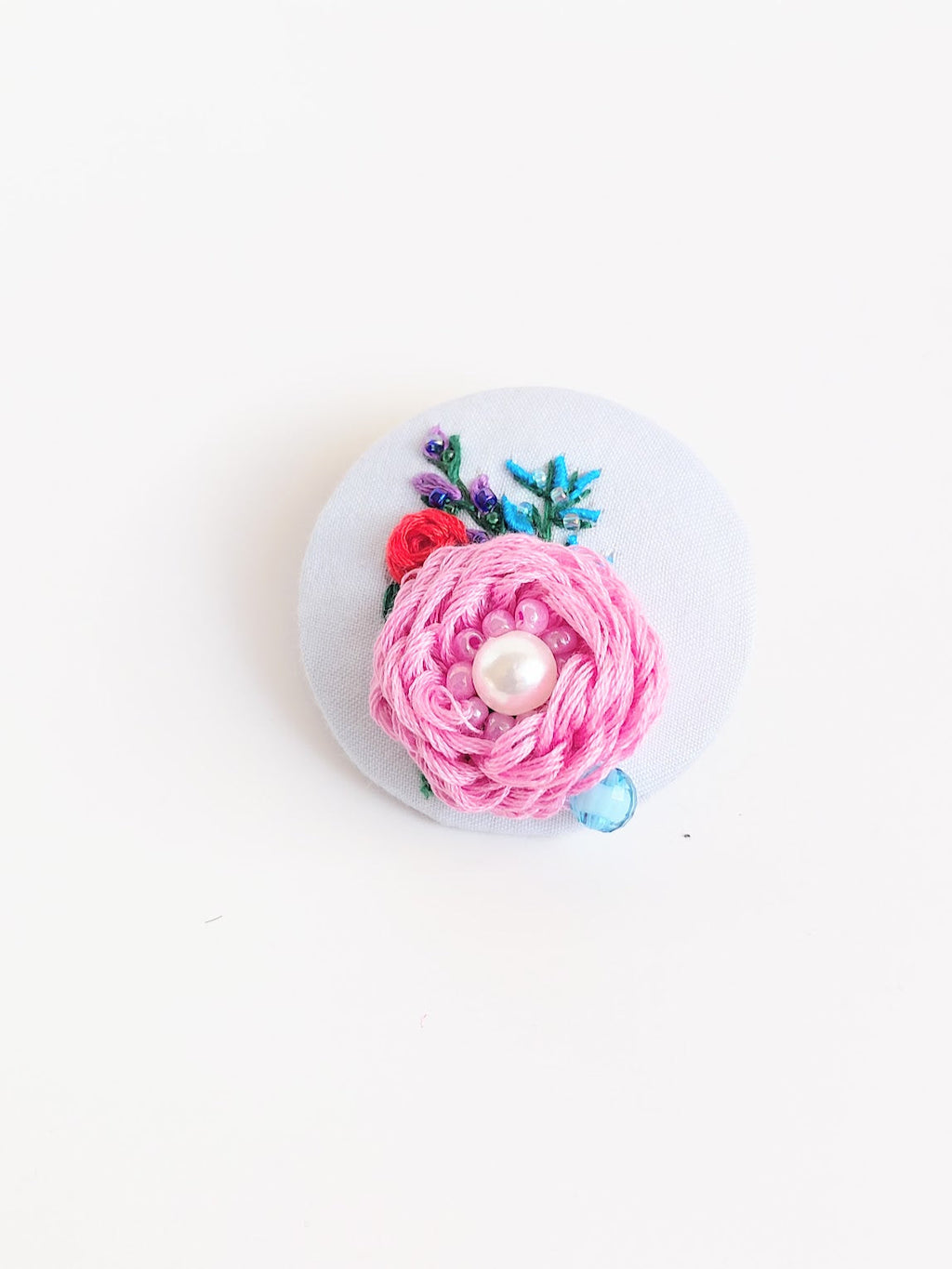 Decorative pink flower brooch on light blue background