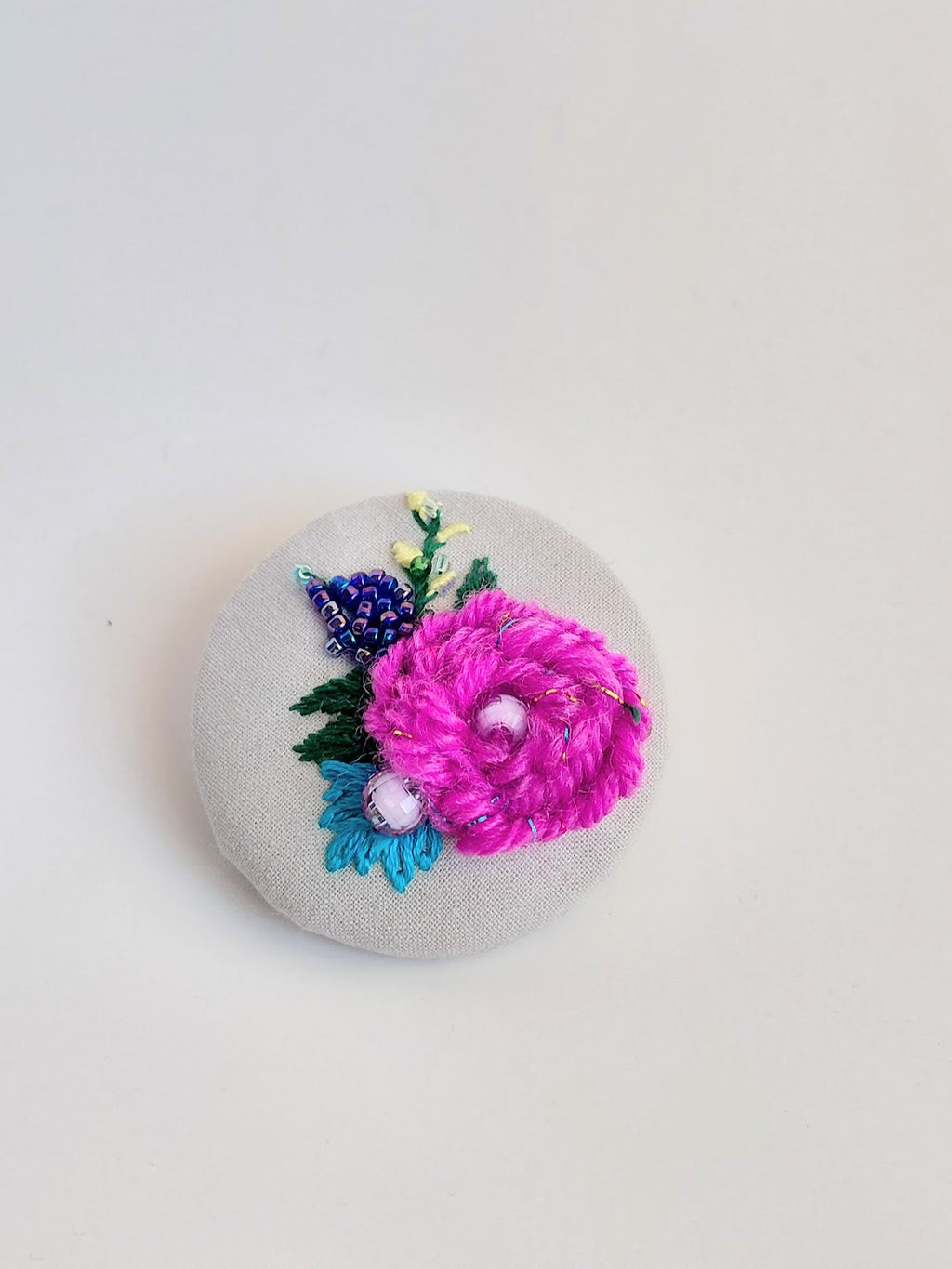 Decorative fuschia flower brooch on grey background