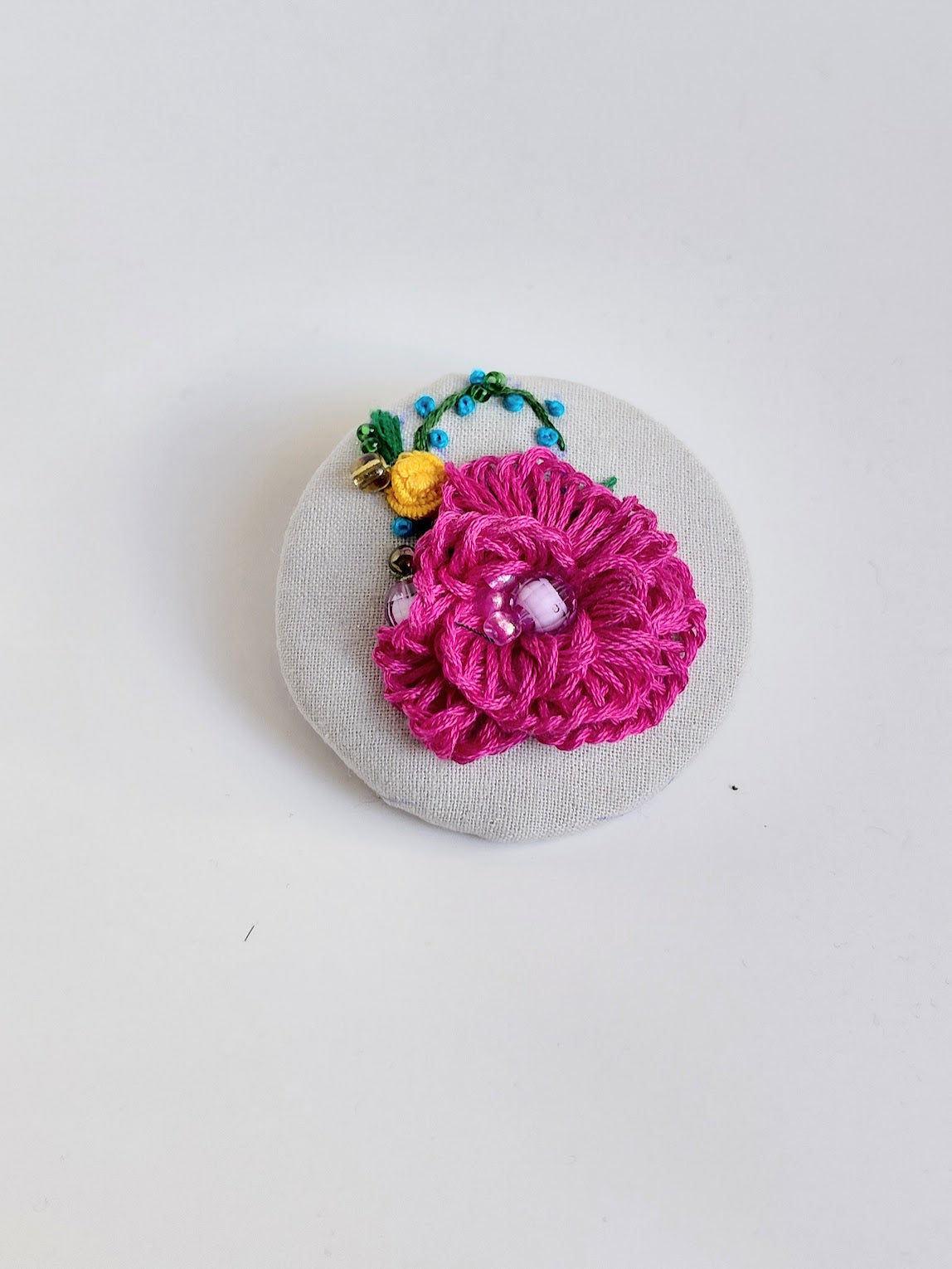 Decorative fuschia flower brooch on grey background