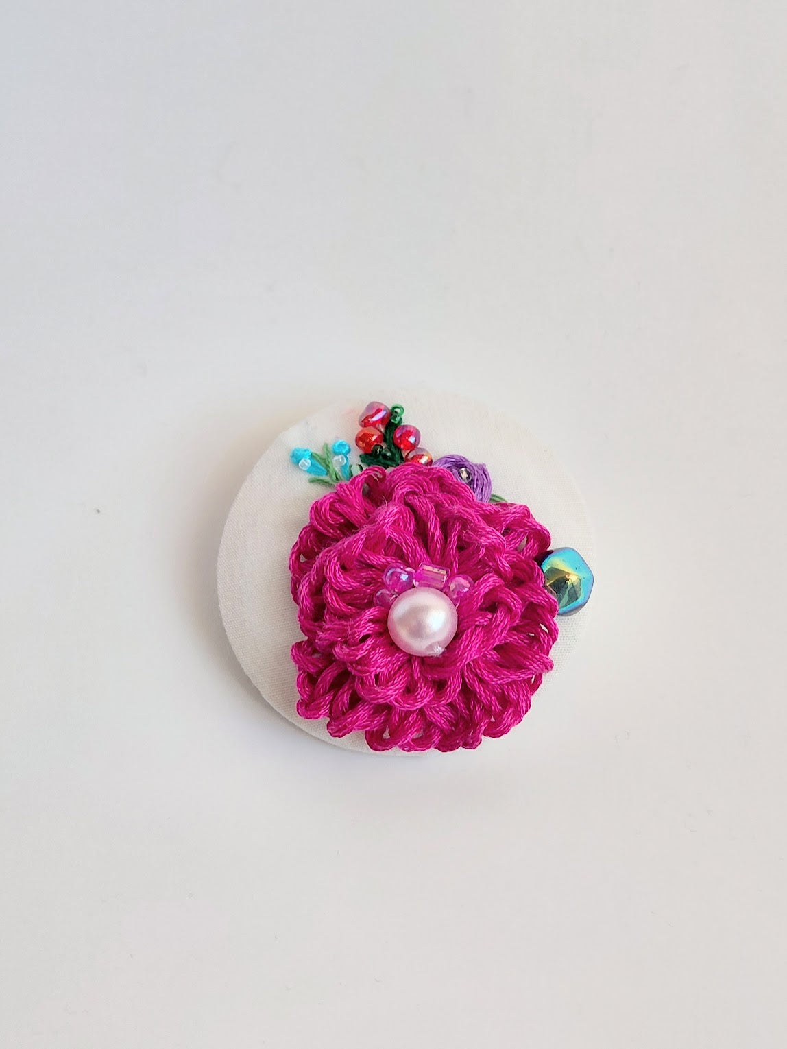 Decorative fuschia flower brooch on white background