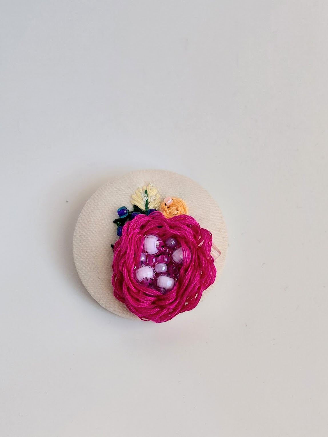 Decorative fuschia flower brooch on cream background