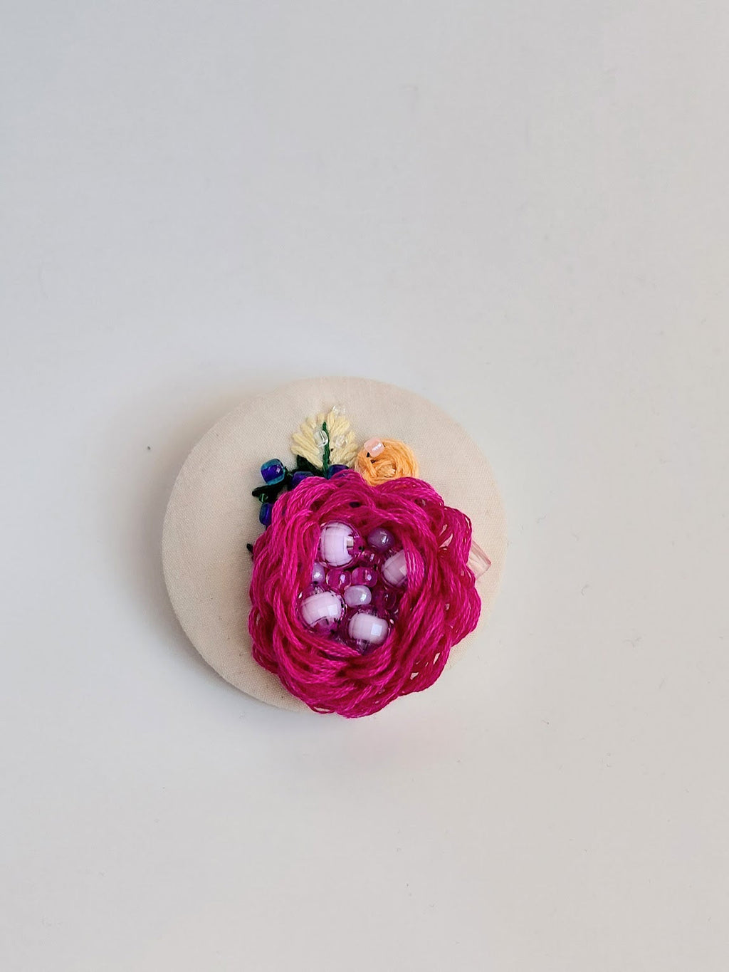 Decorative fuschia flower brooch on cream background