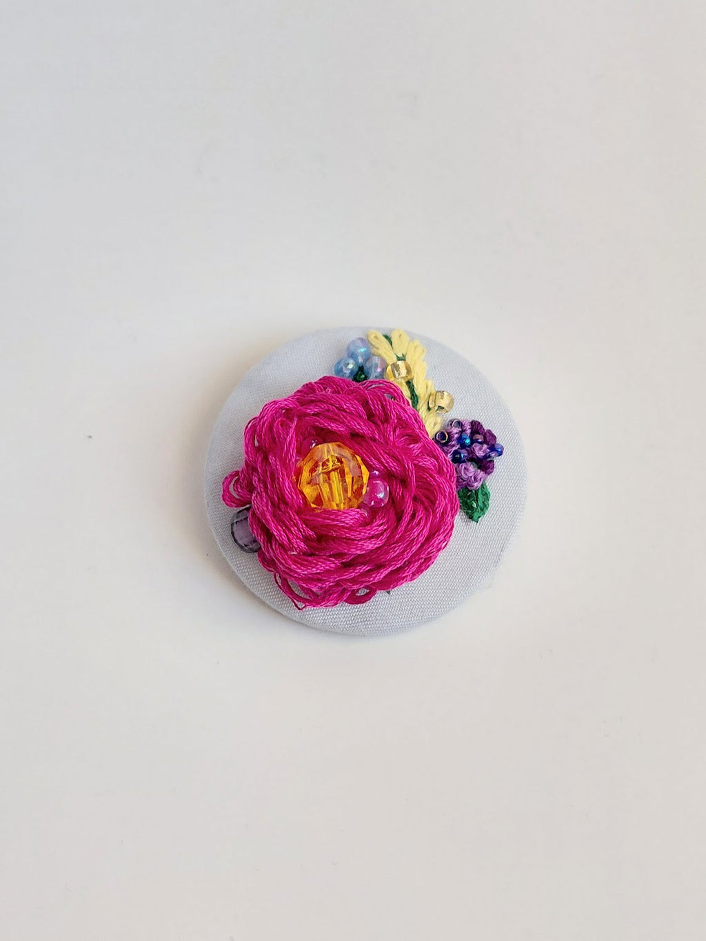 Decorative fuschia flower brooch on light blue background