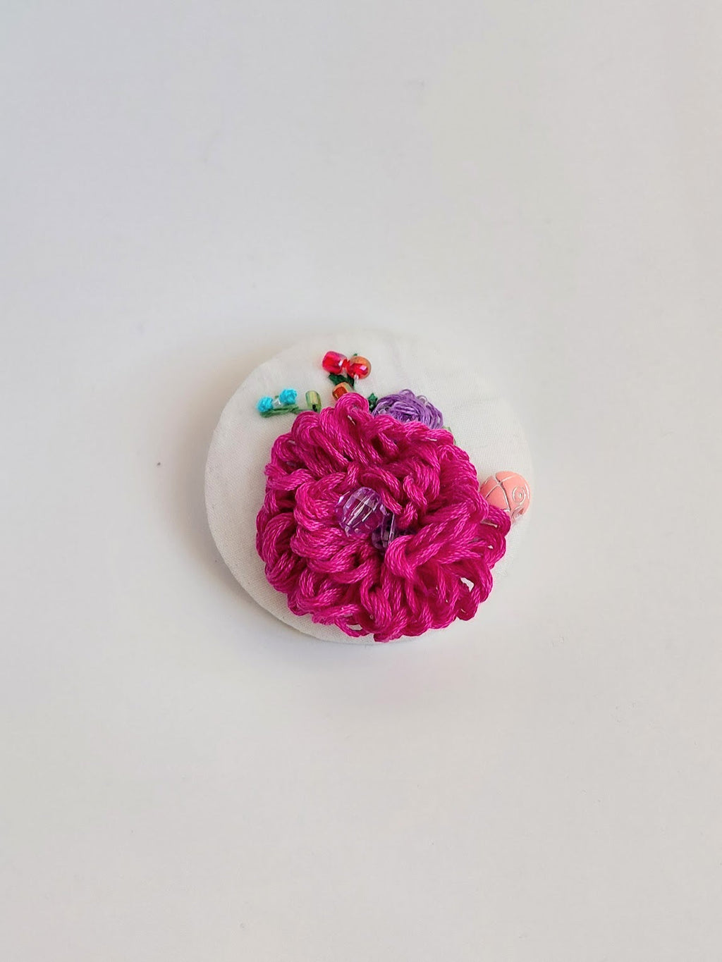 Decorative fuschia flower brooch on white background