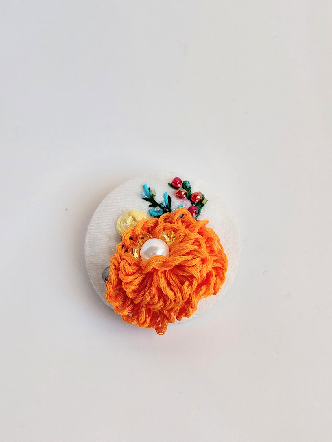 Decorative orange flower brooch on white background
