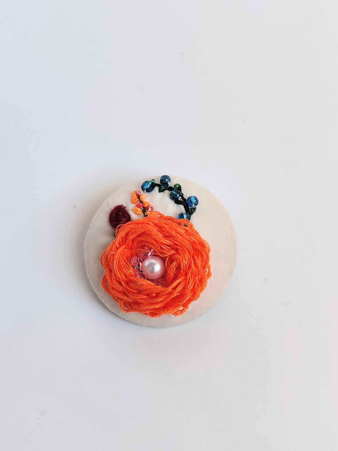 Decorative orange flower brooch on cream background