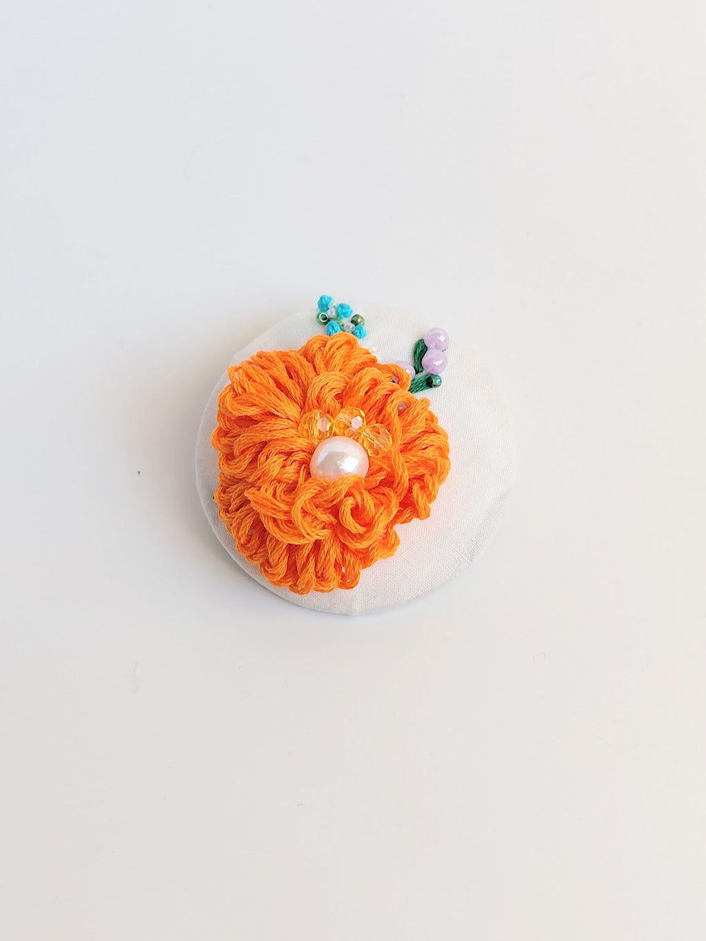 Decorative orange flower brooch on white background