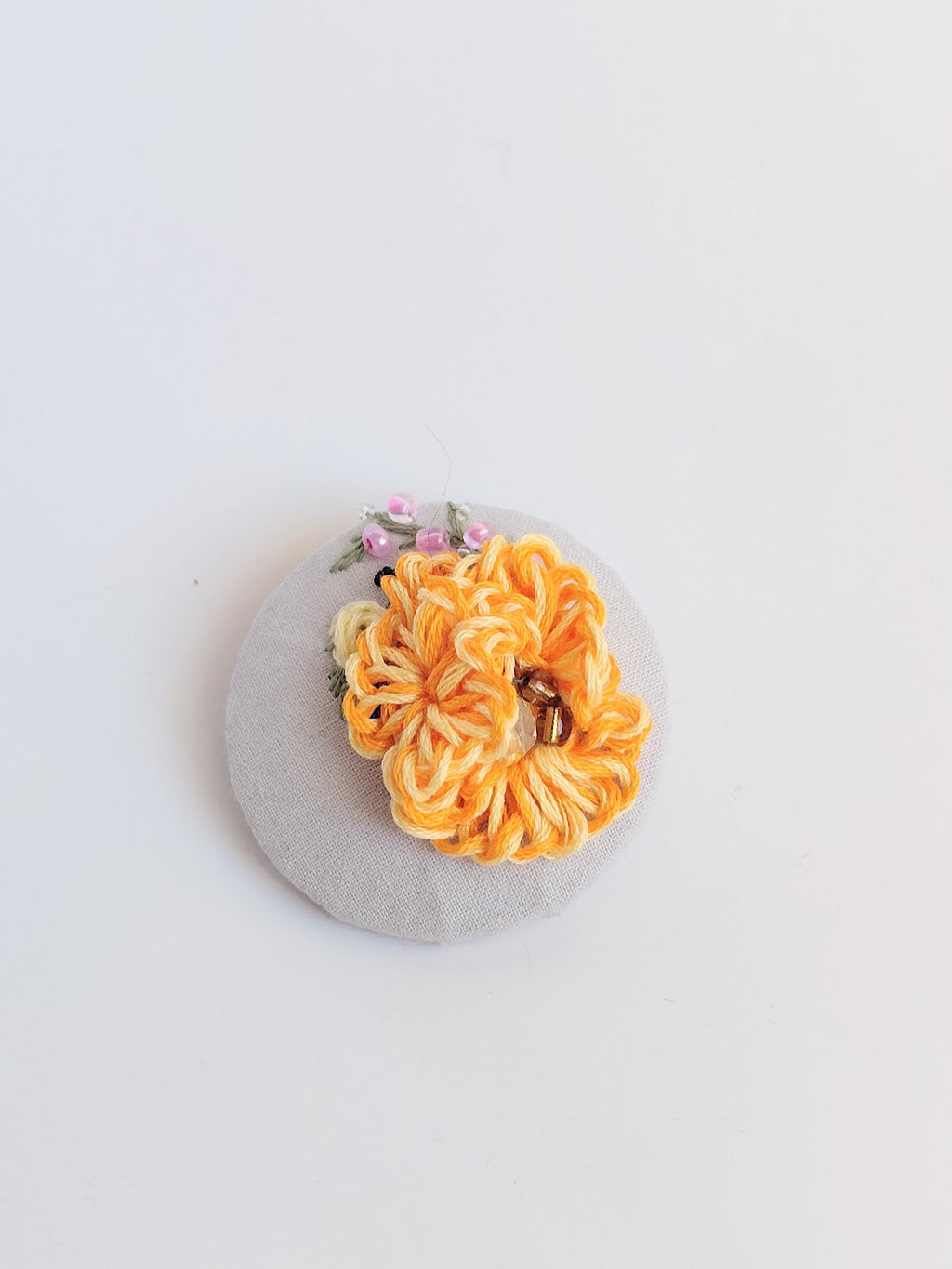 Decorative orange flower brooch on grey background