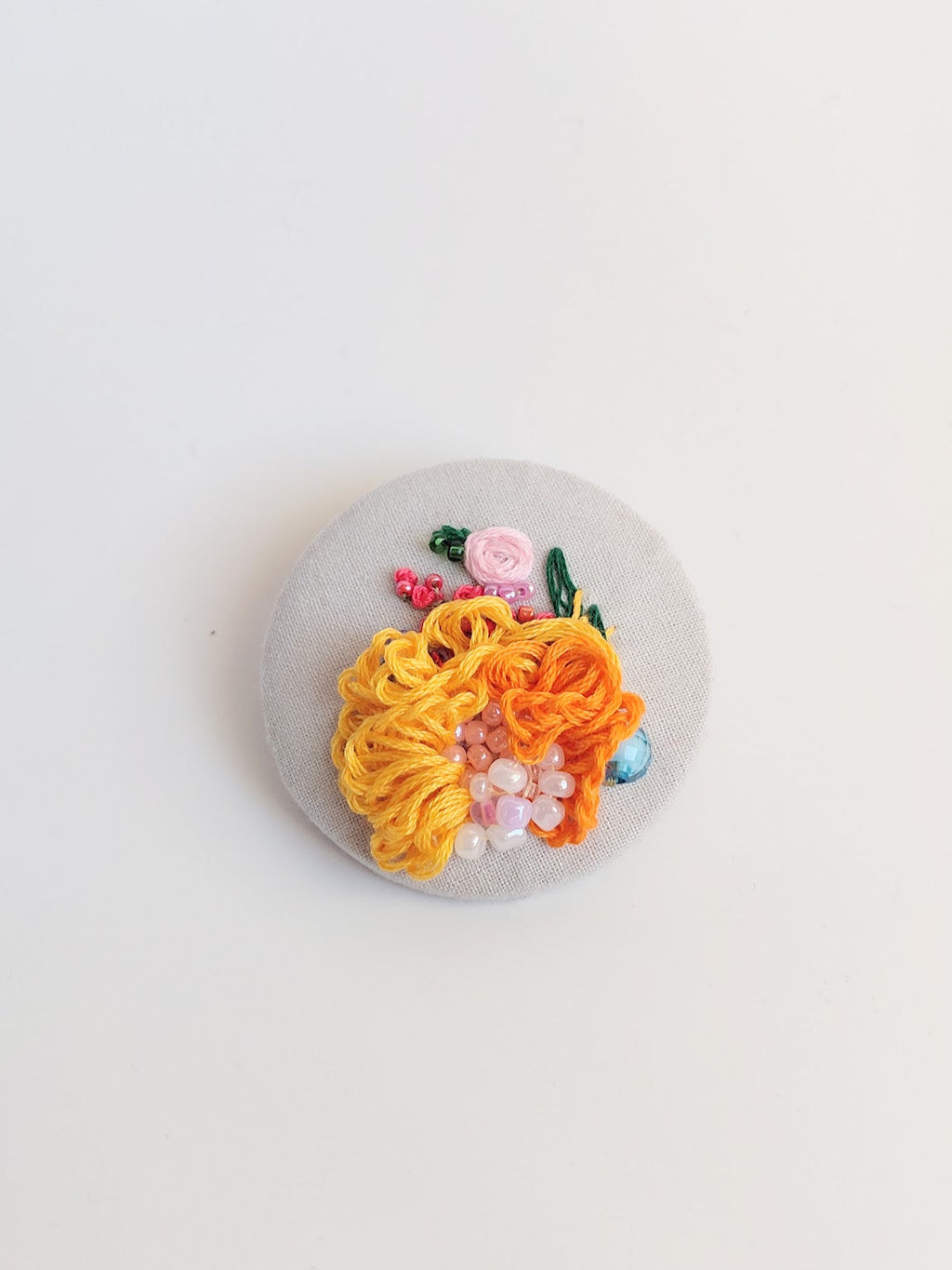 Decorative orange flower brooch on grey background
