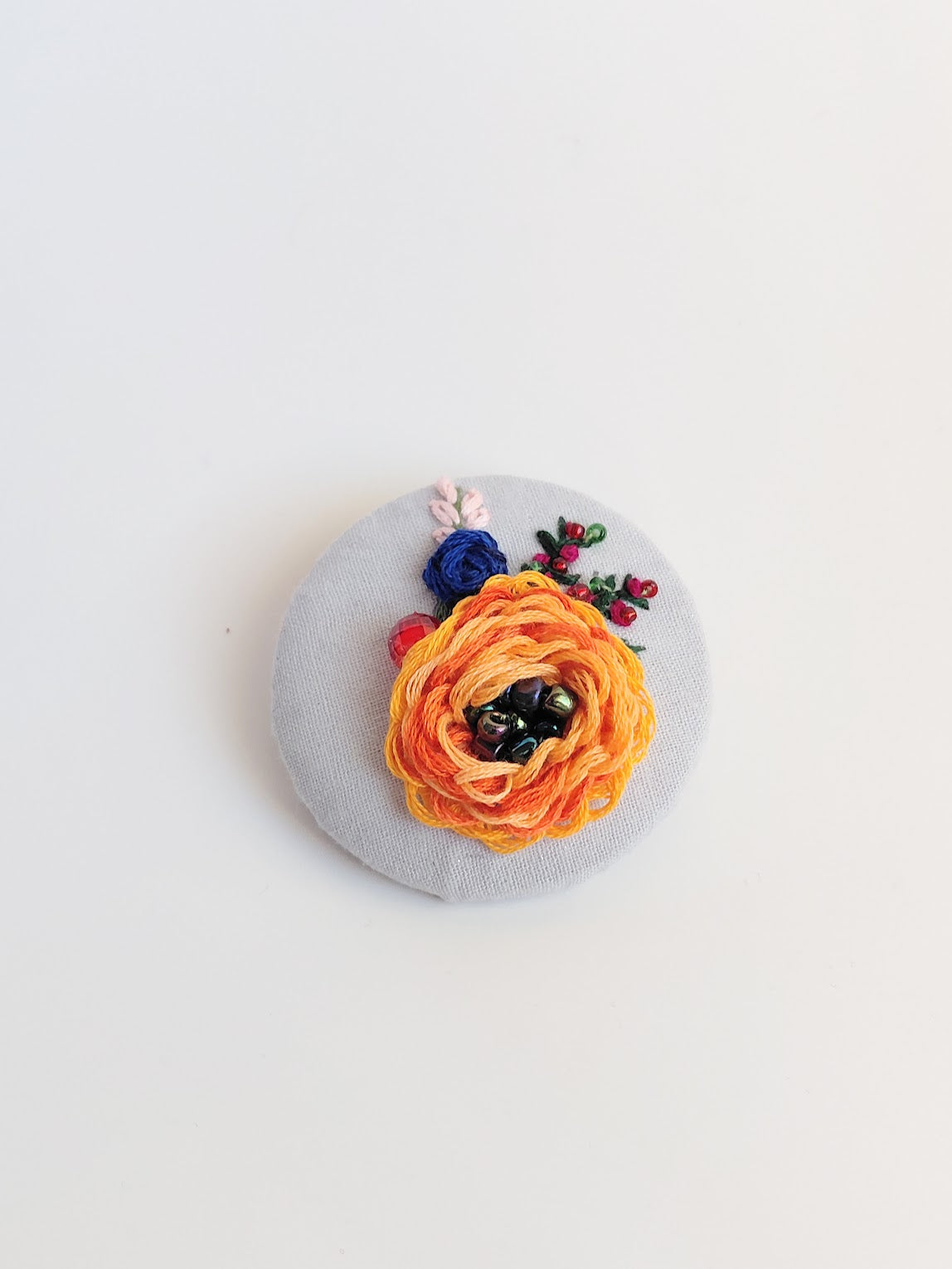 Decorative orange flower brooch on light blue background